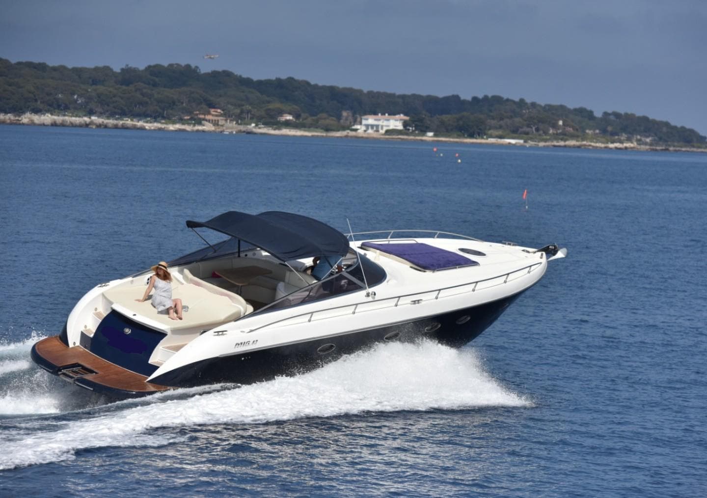 Luxury Mig 43 yacht cruising on open water, 2010 model, with scenic coastline in background.