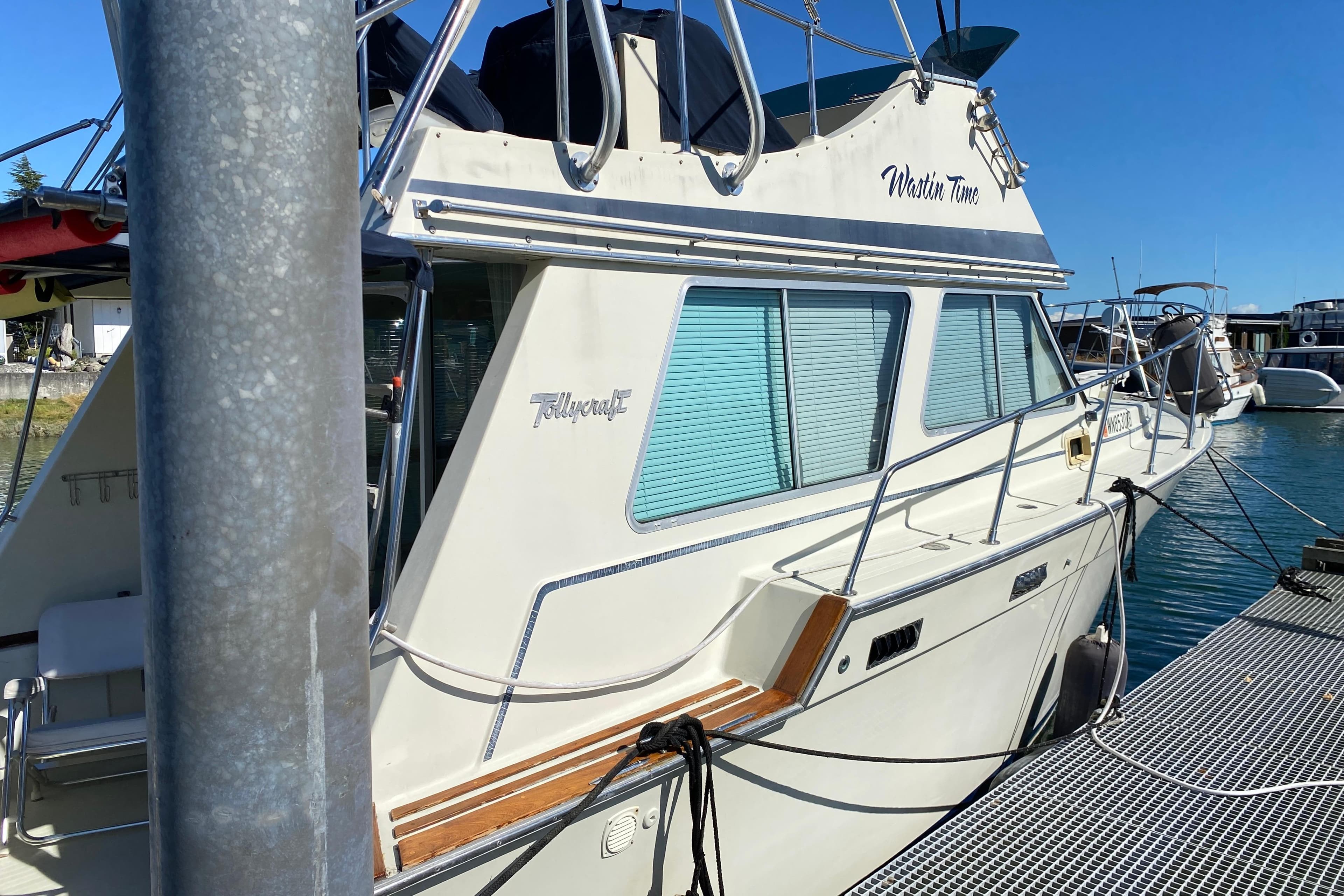 1984 Tollycraft 34 Convertible Sedan docked at marina under clear blue sky.