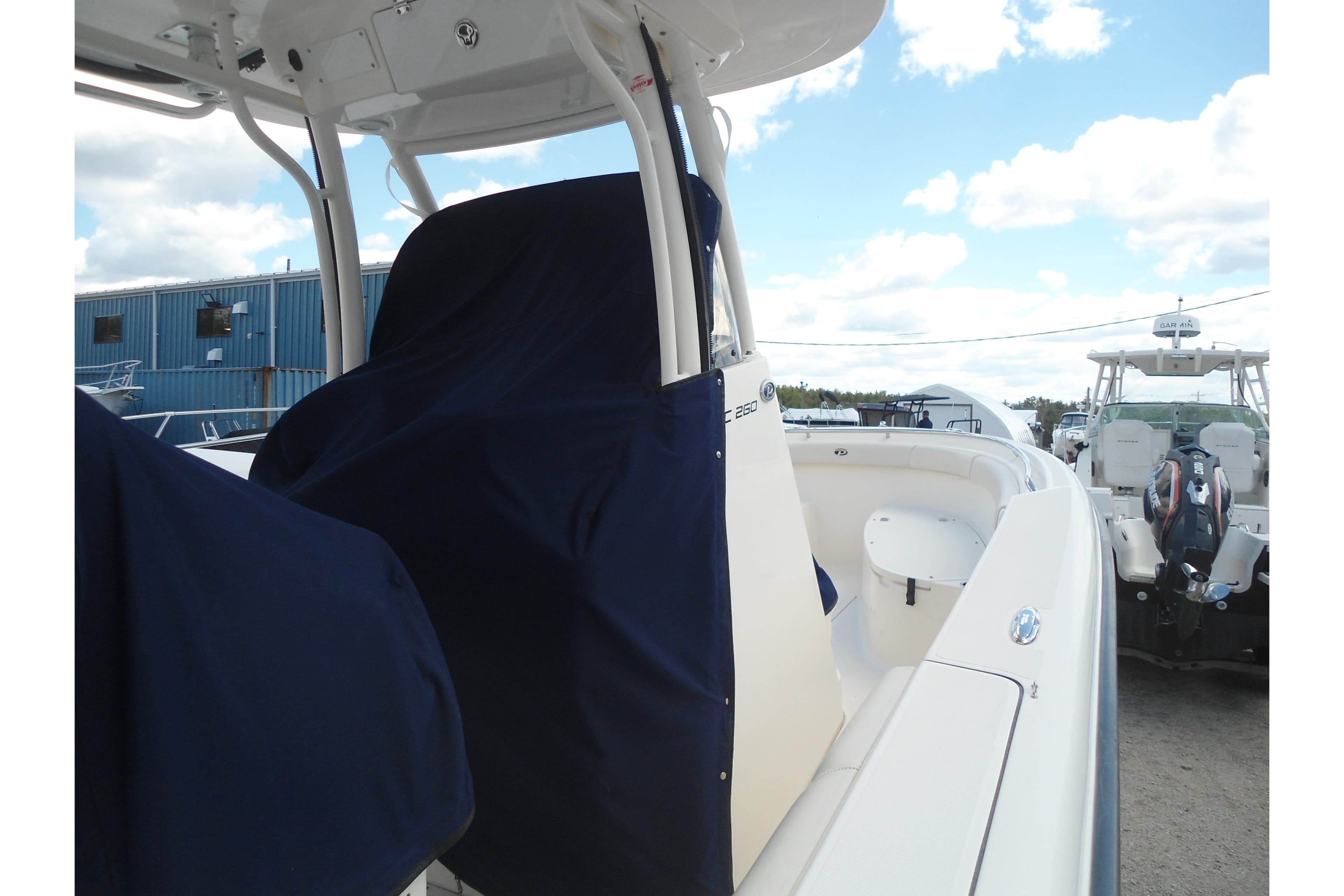 2013 Pursuit C 260 Center Console boat with covered seating, docked under a cloudy sky.