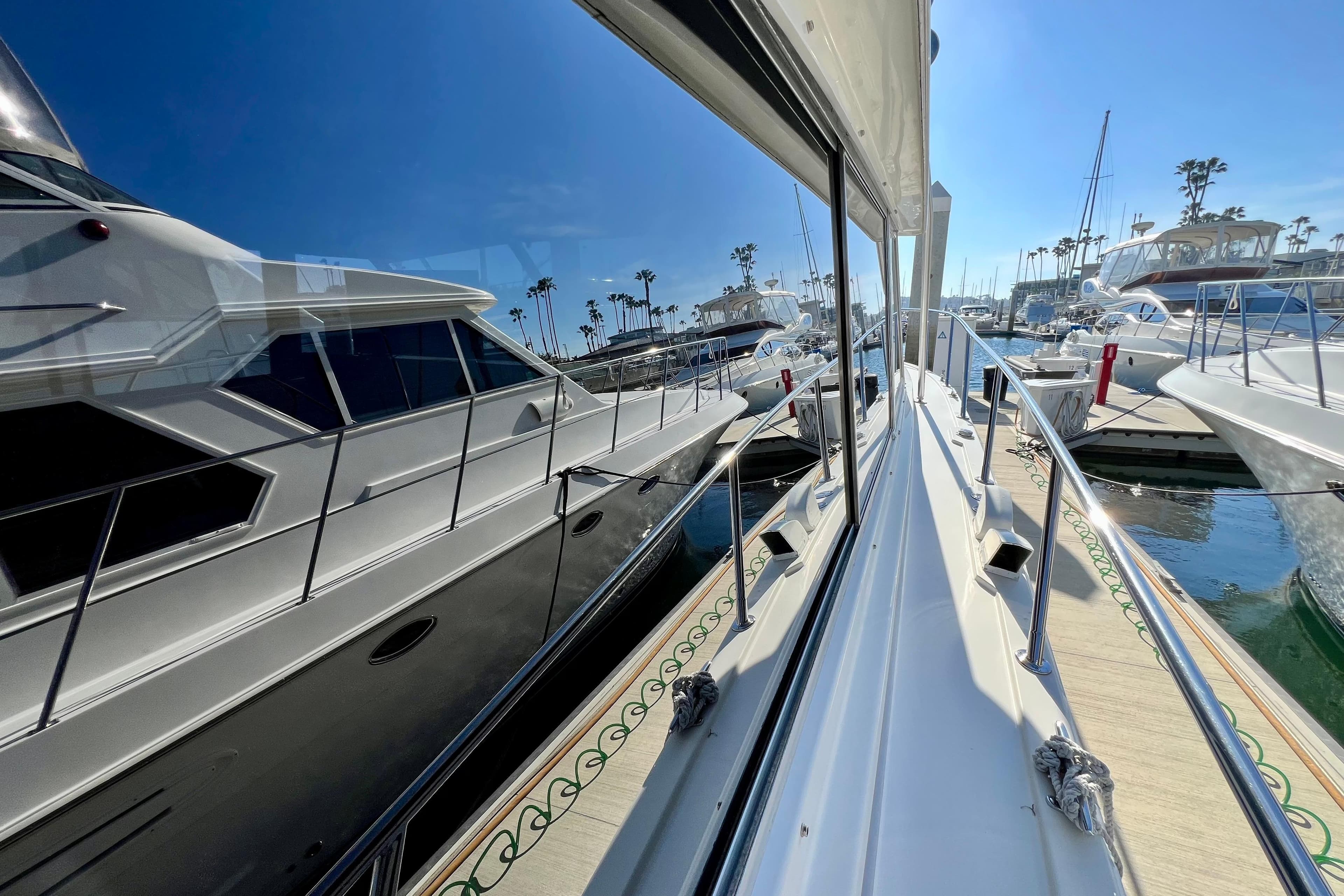 1982 Bertram 46 Convertible yacht docked in a sunny marina, reflecting on calm water.