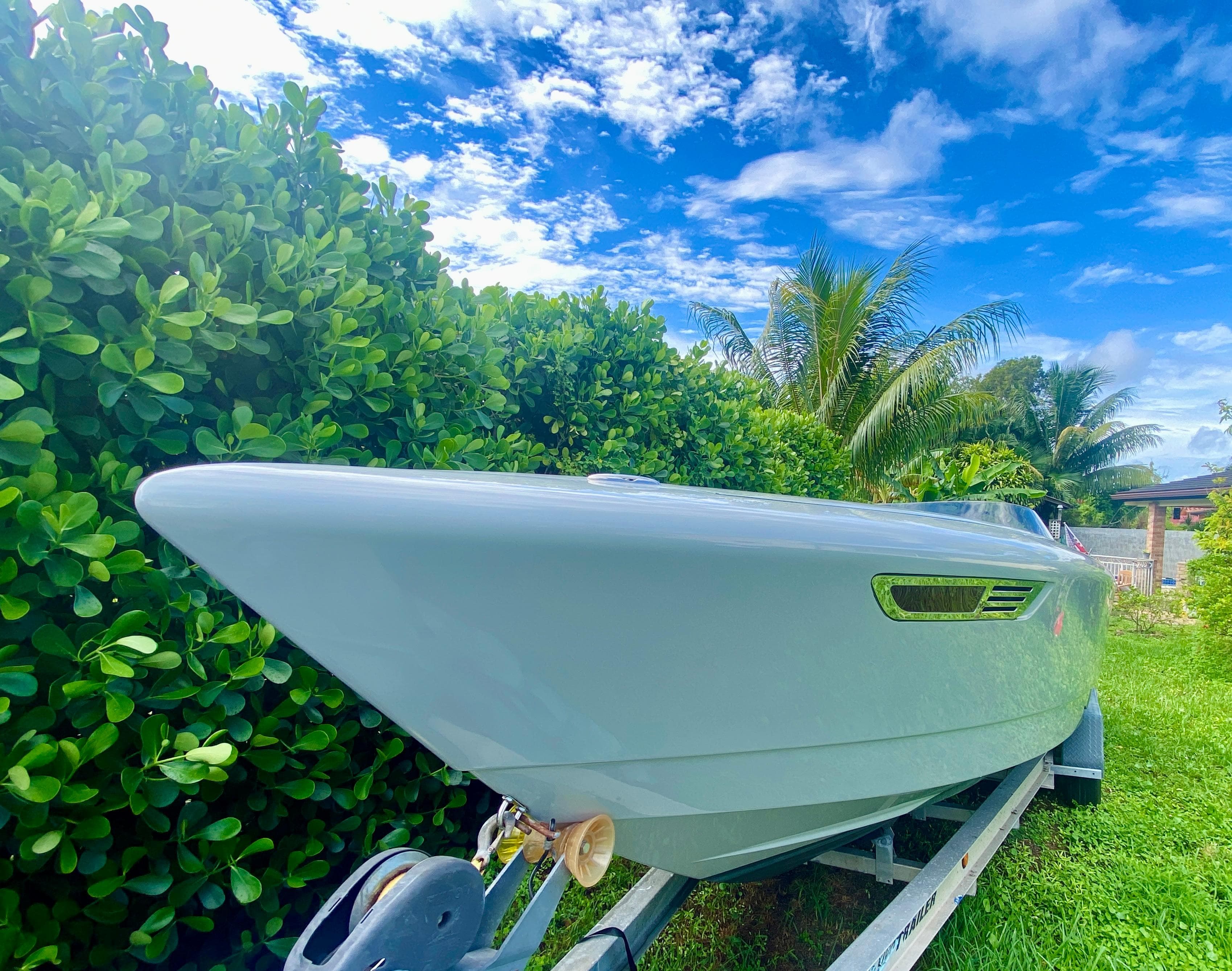 2008 Porsche Fearless 28 boat on trailer, surrounded by lush greenery and blue sky.