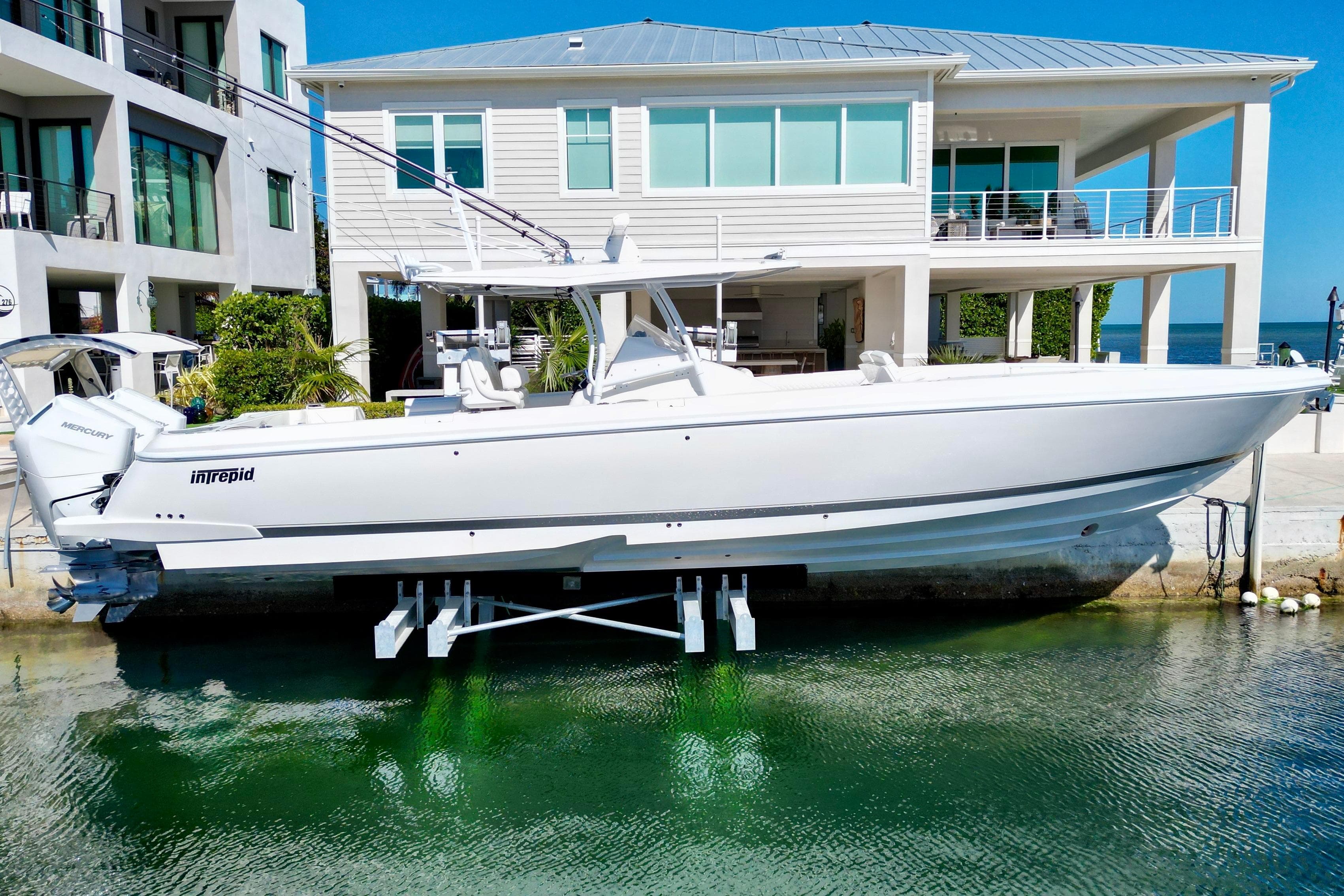 2024 Intrepid 407 Nomad FE boat docked near modern waterfront home.
