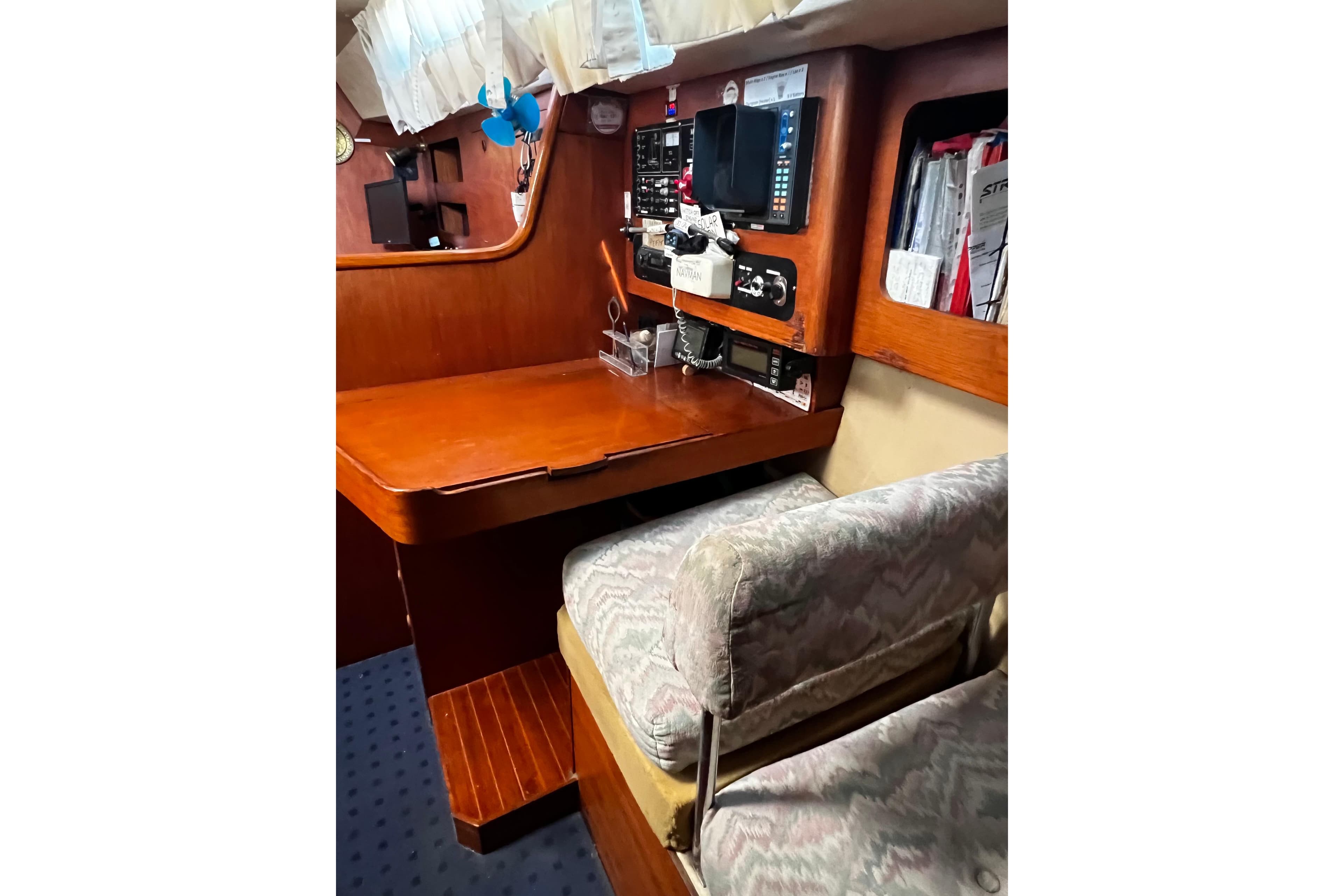 Navigation station inside a 1990 Moody 376 sailboat with wooden desk and equipment.