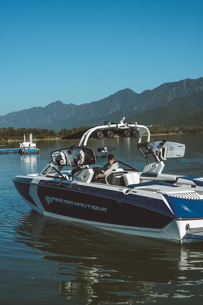 2017 Nautique Super Air Nautique G25 boat on a serene lake with mountain backdrop.