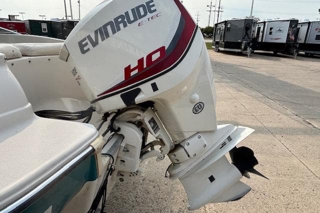 Evinrude E-TEC HO outboard motor on 2000 Glastron GX 180 boat, parked outdoors.