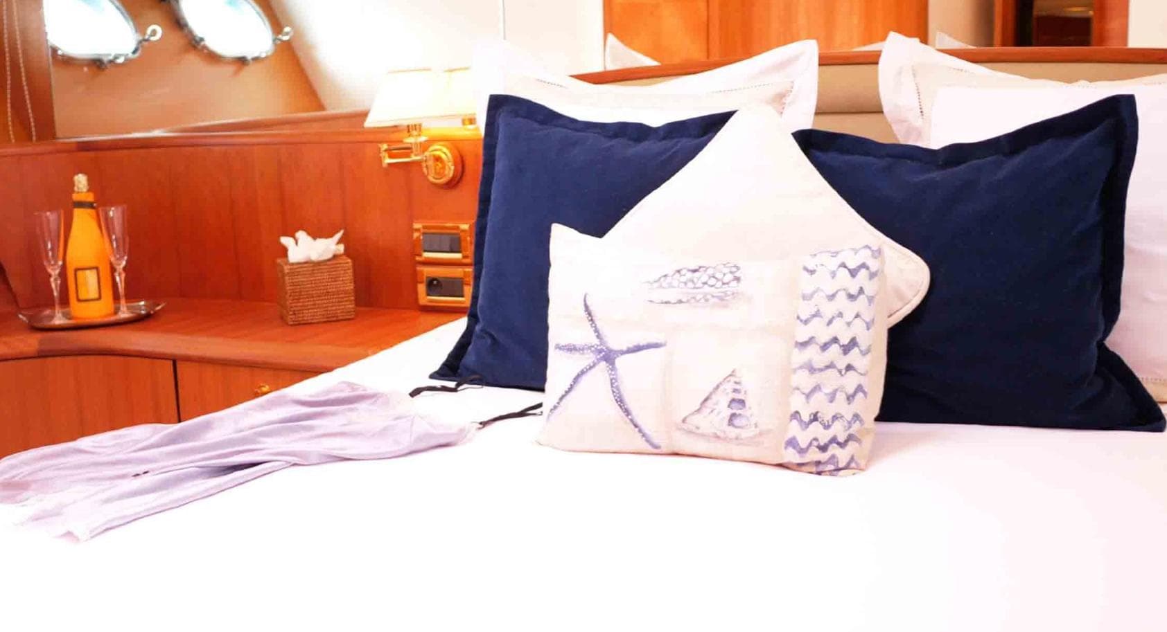 Luxurious bedroom interior on 2006 Couach 3000 Fly yacht with nautical-themed pillows.