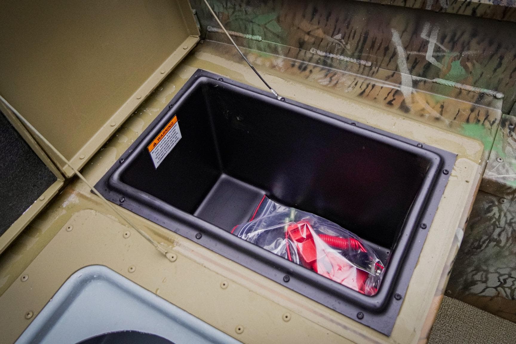 Storage compartment in 2026 G3 17SC boat, featuring a plastic bag with red accessories.