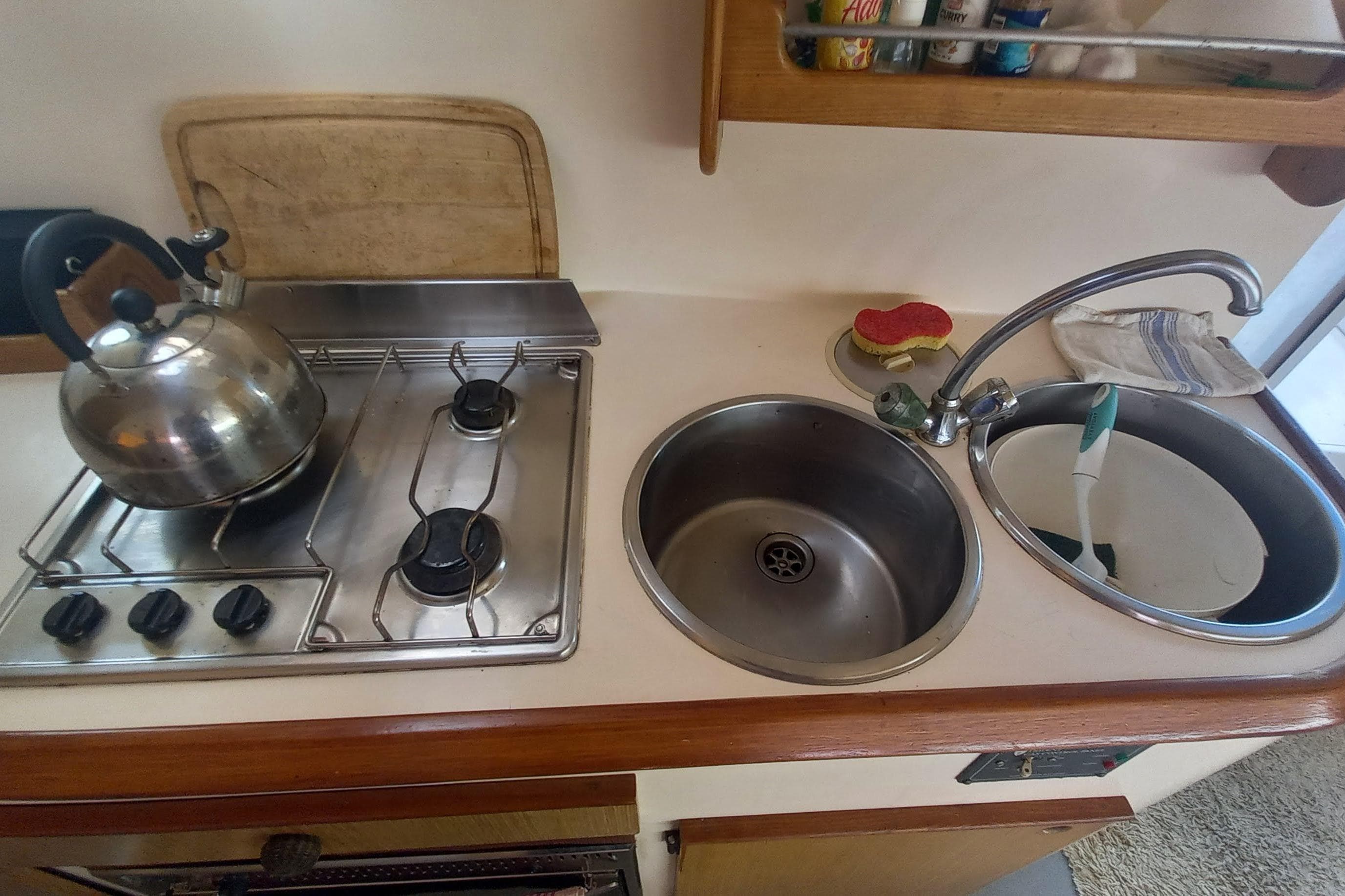 Compact kitchen area in a 1993 Fountaine Pajot Antigua 37 catamaran, featuring stove and sink.