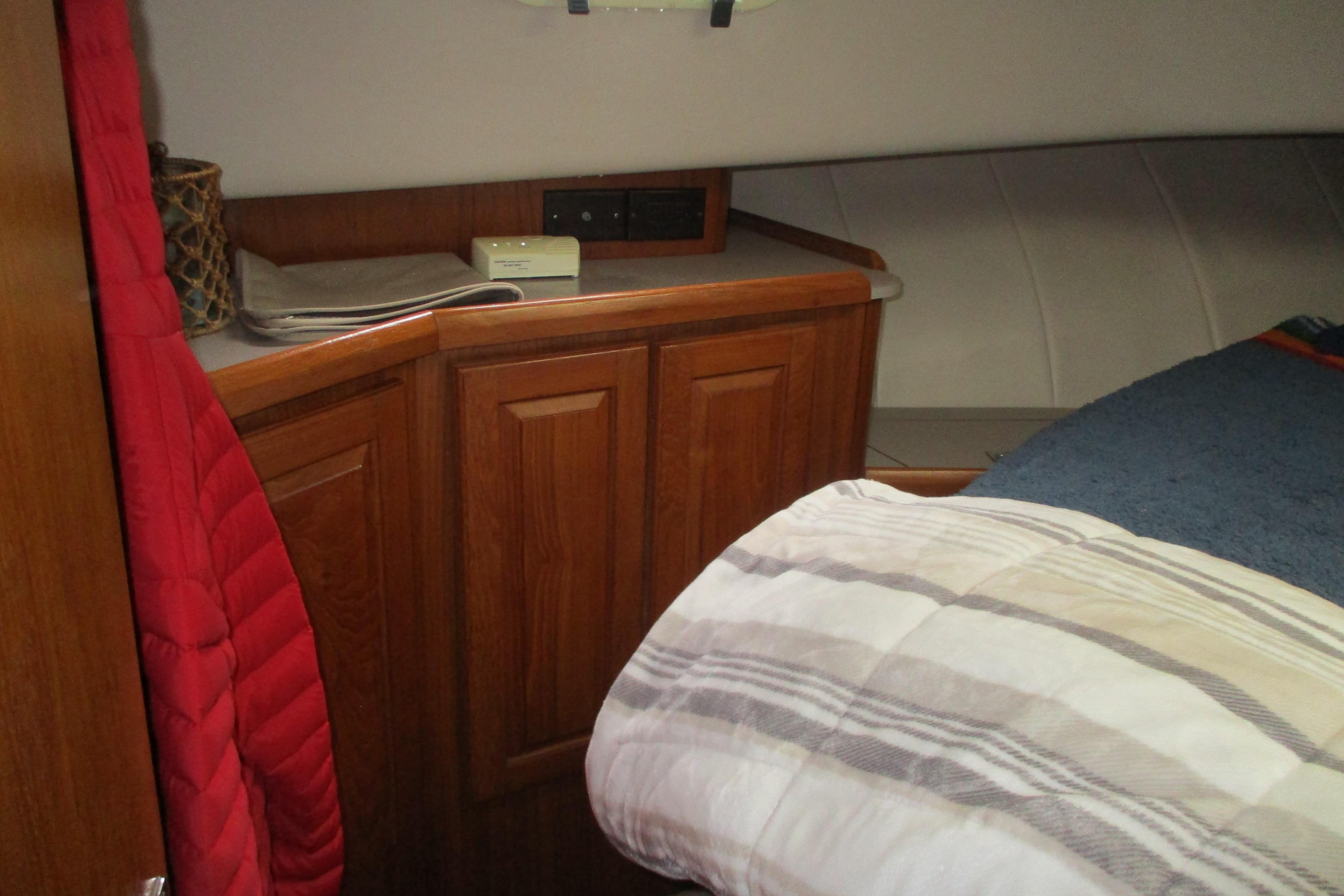 Cozy cabin interior of 1997 Mainship 350 Trawler with wooden cabinetry and bedding.