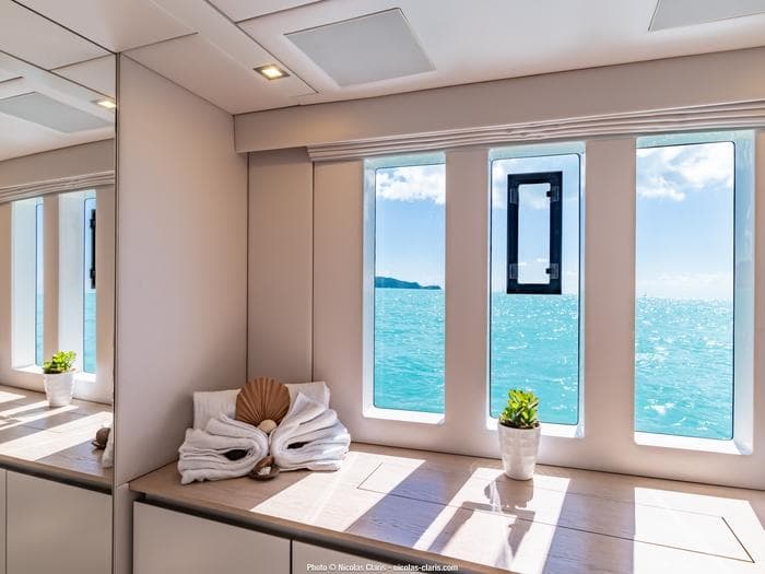 Luxurious Sunreef Supreme 68 yacht interior with ocean view, featuring elegant decor and natural light.