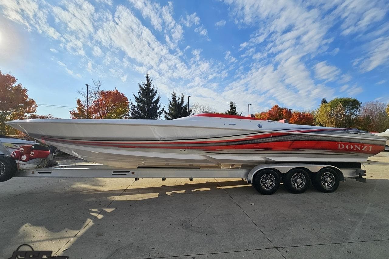 2008 Donzi 38 ZR speedboat on trailer, vibrant red and white design, under clear blue sky.