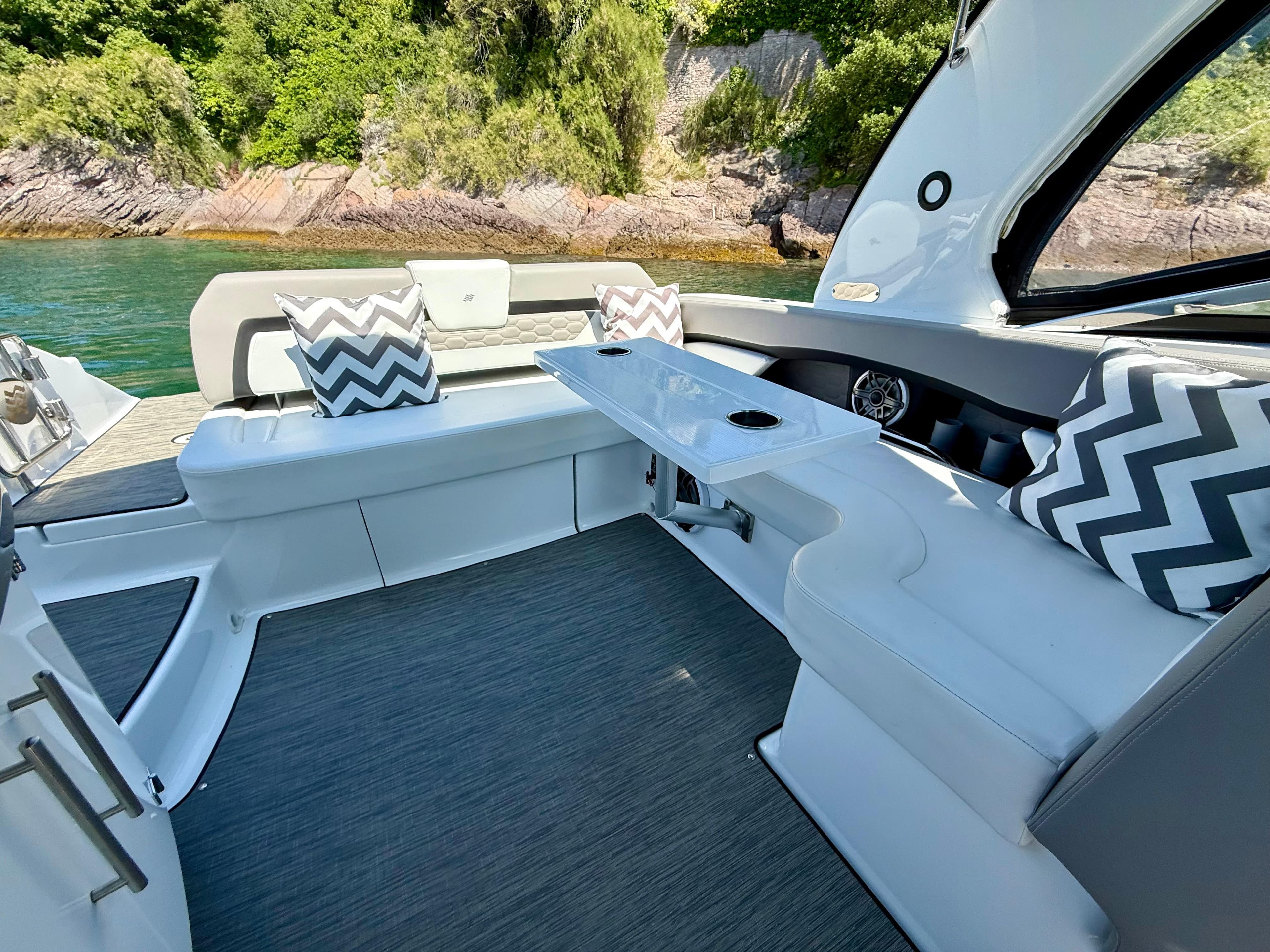 Luxurious 2023 Four Winns H290 boat interior with stylish seating and scenic water view.