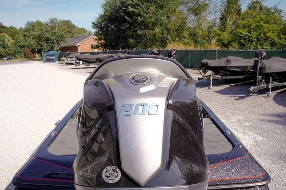 2026 Skeeter ZX200 boat engine, parked outdoors on gravel, surrounded by trees and trailers.