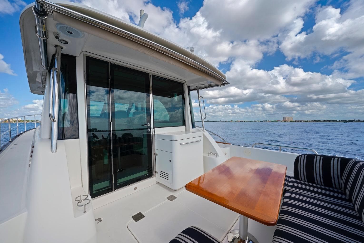 2019 Sabre 45 Salon Express yacht deck with table, striped seating, and ocean view.