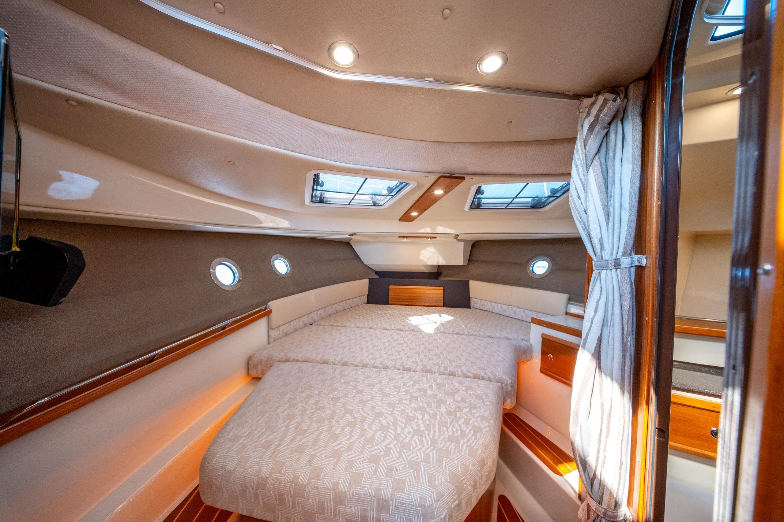 2023 Ranger Tugs R-29 CB cabin interior with cozy bed and elegant wood finishes.