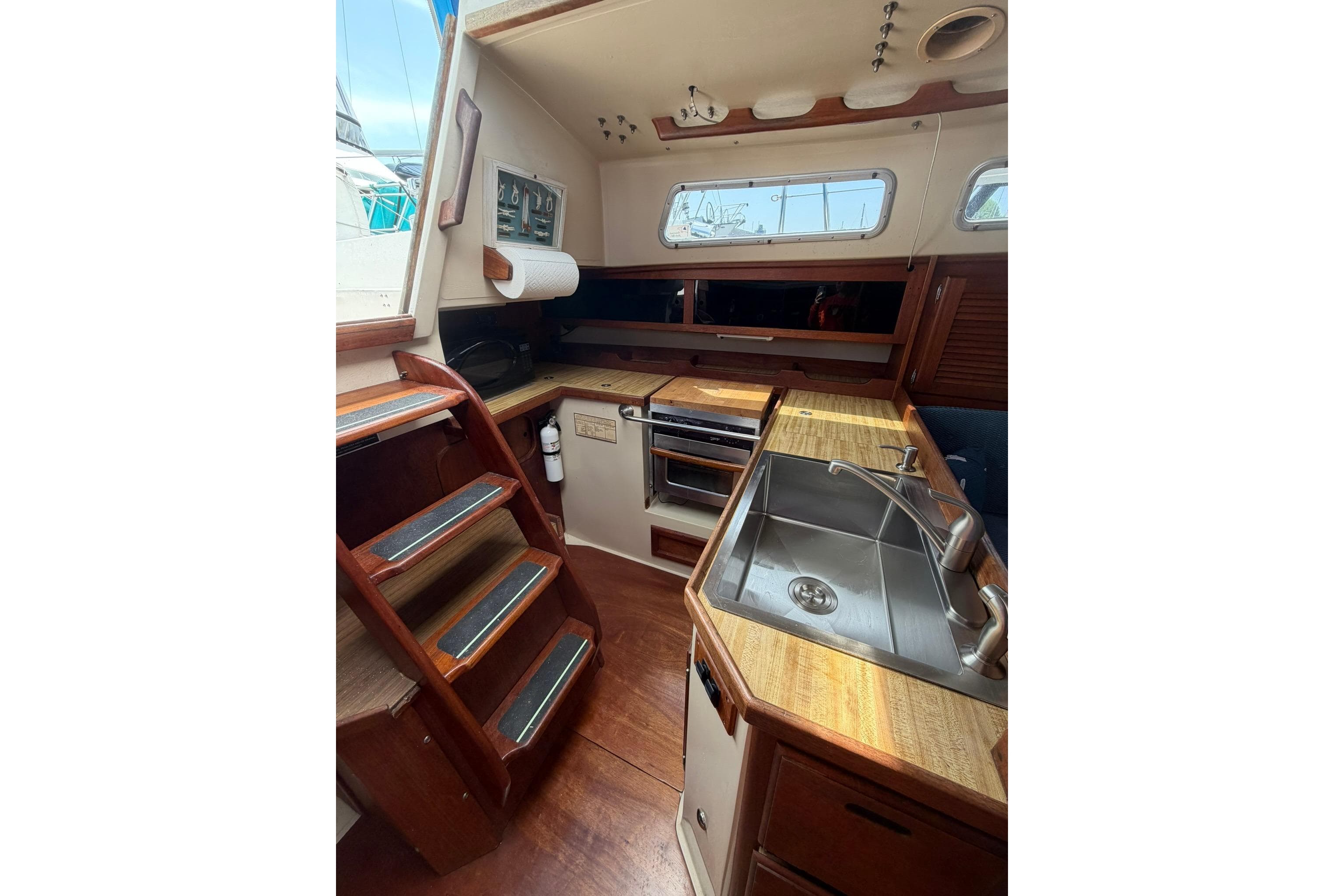 Interior of 1985 Catalina 36 sailboat featuring kitchen area with sink and wooden cabinetry.