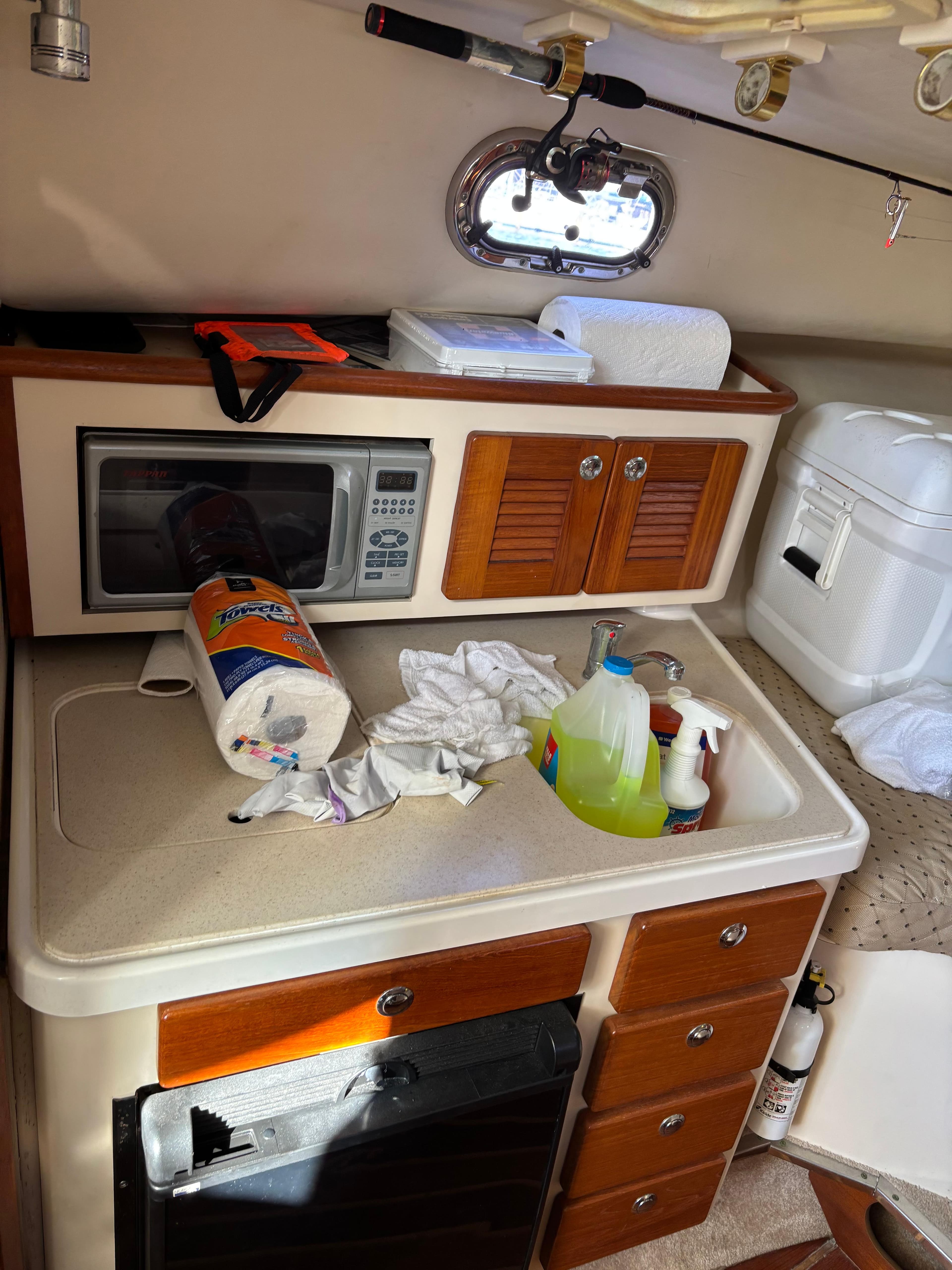 2006 Pursuit 3370 Offshore cabin kitchen with microwave, cleaning supplies, and storage cabinets.