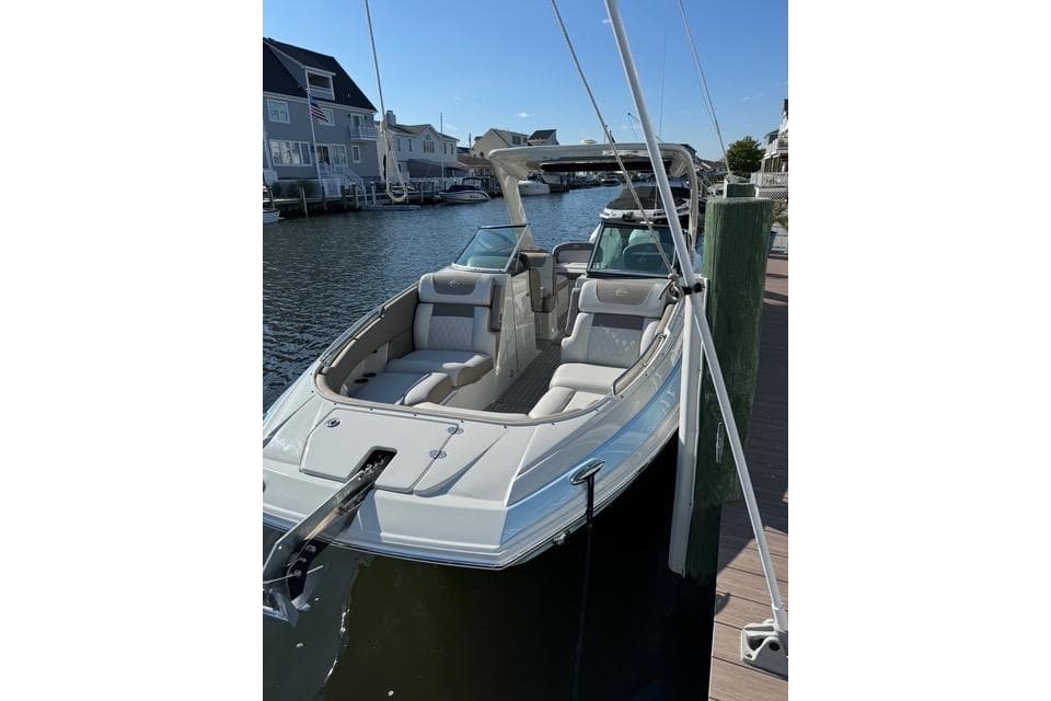 2023 Crownline Eclipse E305 XS boat docked in a scenic waterfront setting.