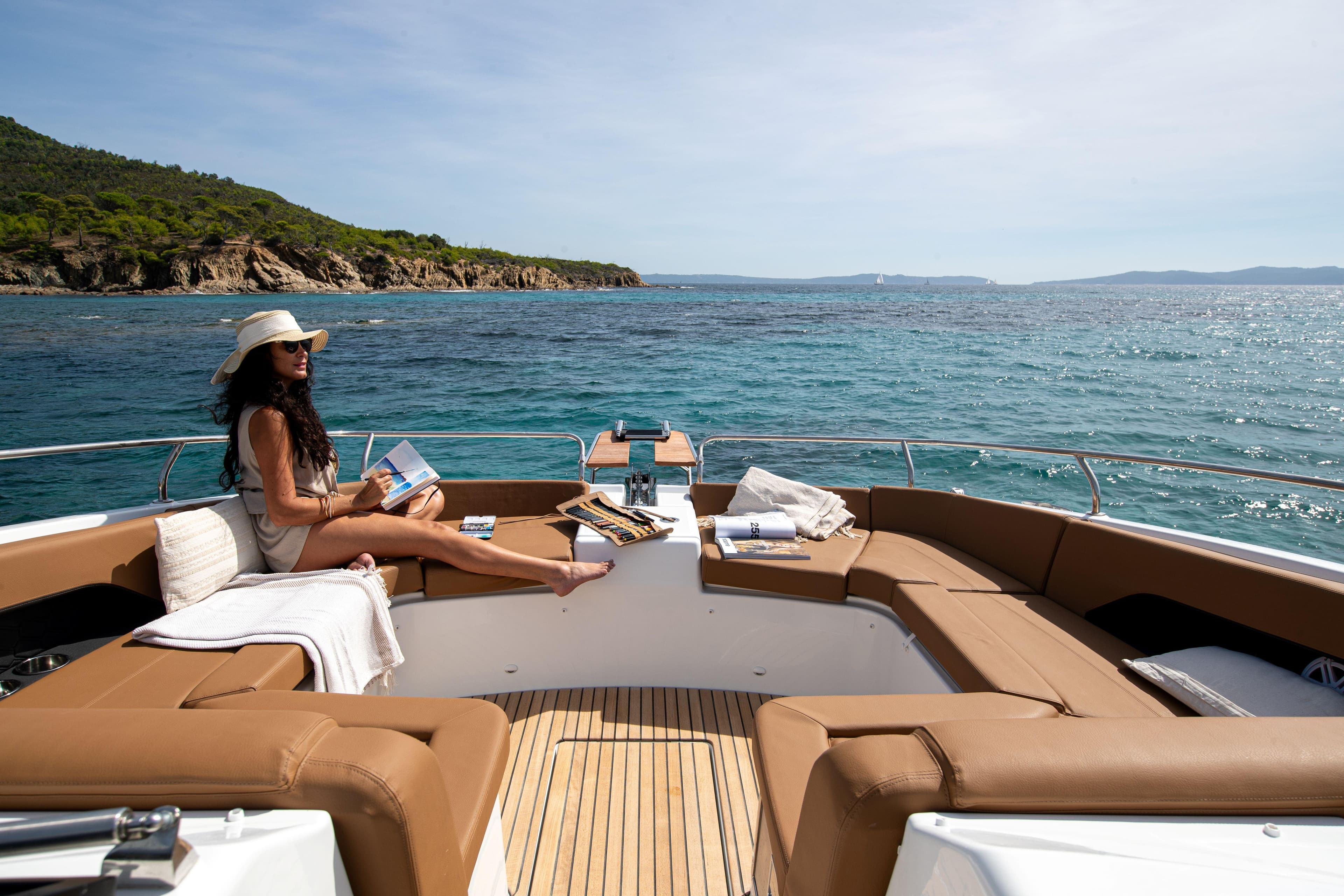 Woman relaxing on Jeanneau TH38 yacht, 2026 model, with scenic ocean view.