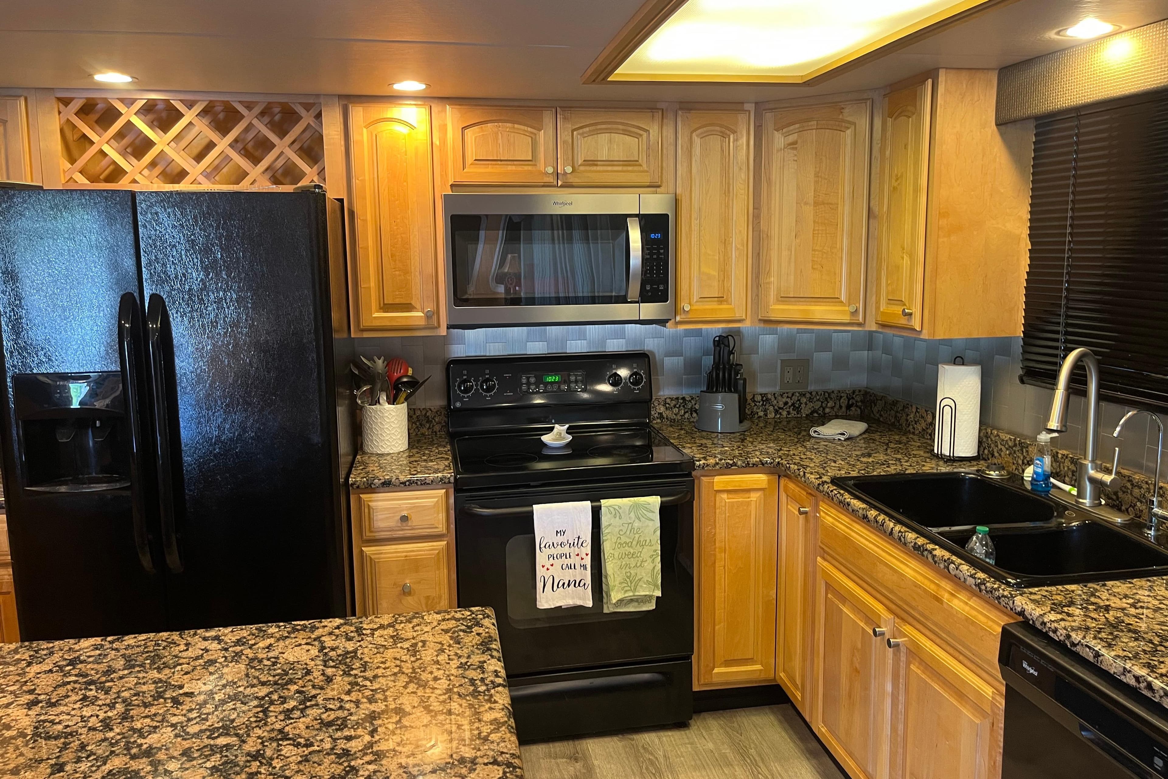 Modern kitchen with wooden cabinets, granite countertops, and black appliances, featuring a Majestic Legacy 2005 model.