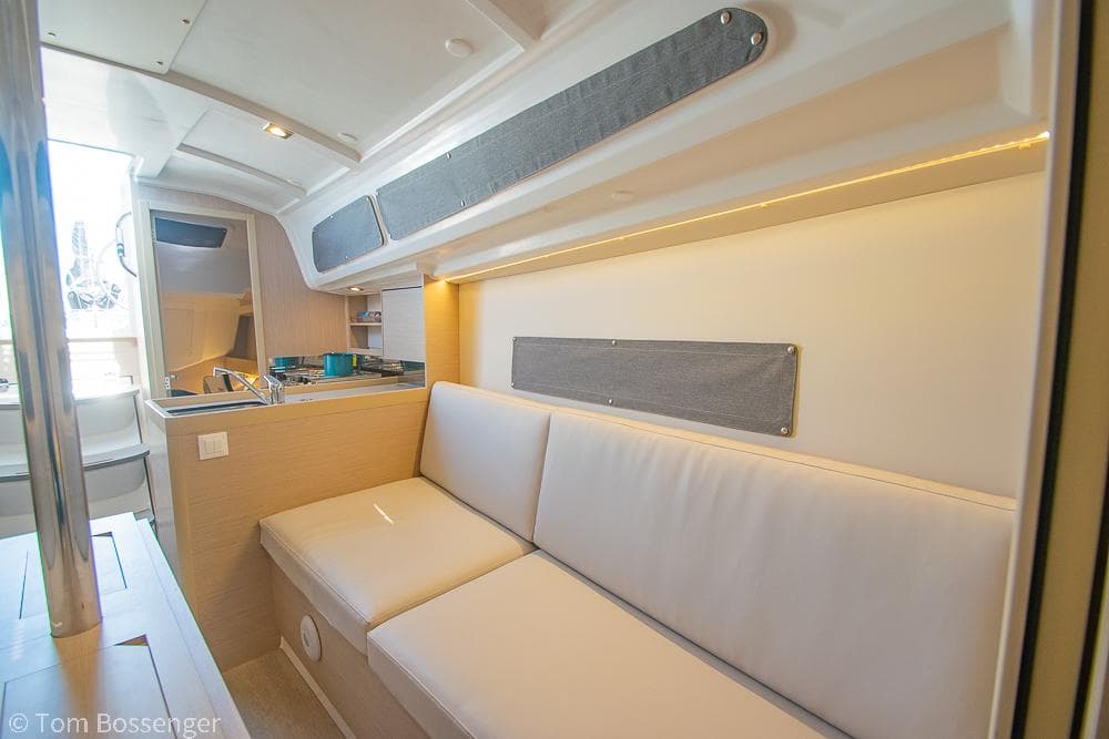 Interior of 2022 Beneteau Oceanis 30.1 yacht, featuring a cozy seating area and kitchenette.