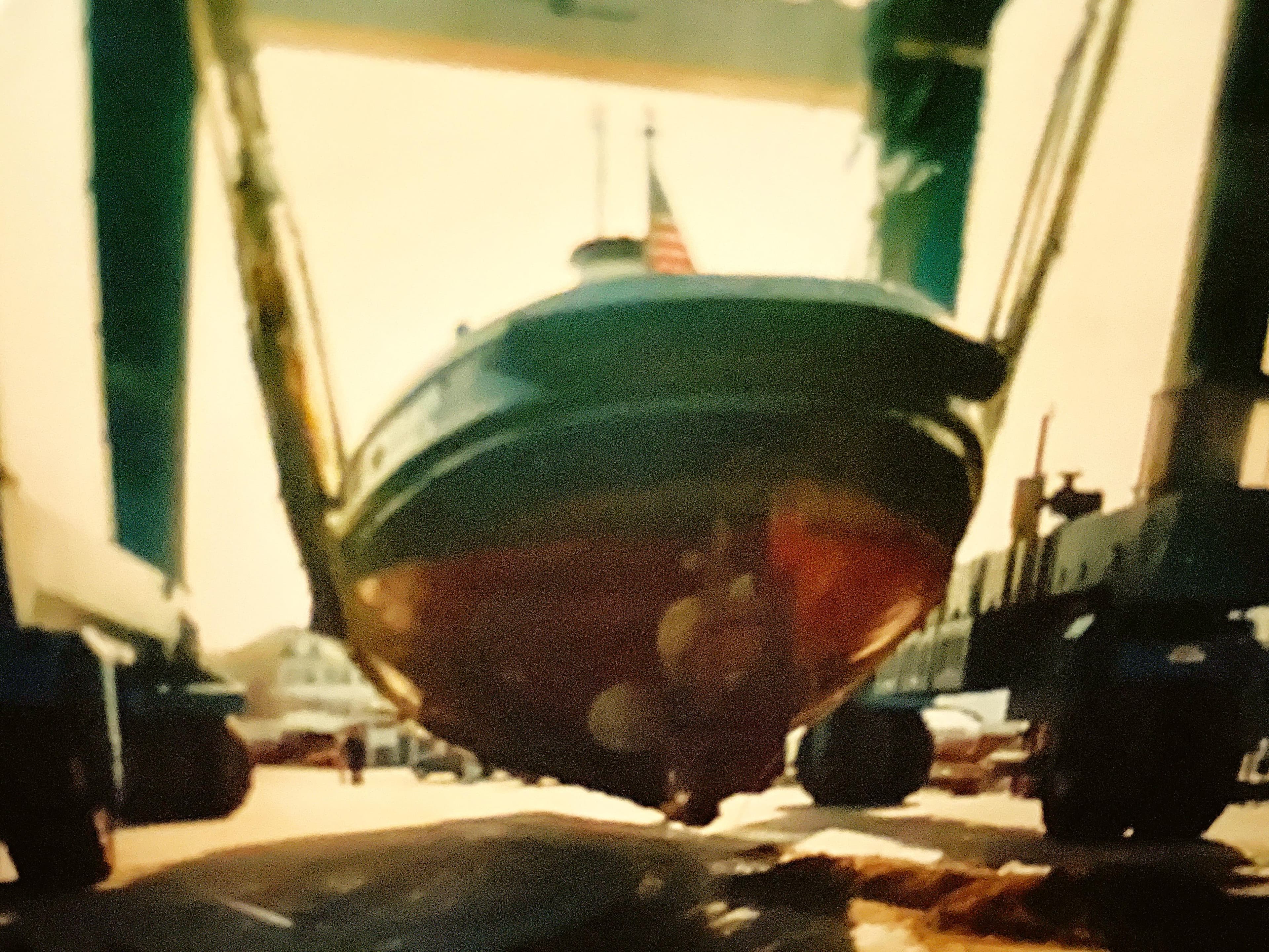 Historic 1936 Bow Steel tugboat being lifted by crane, displaying its hull and American flag.