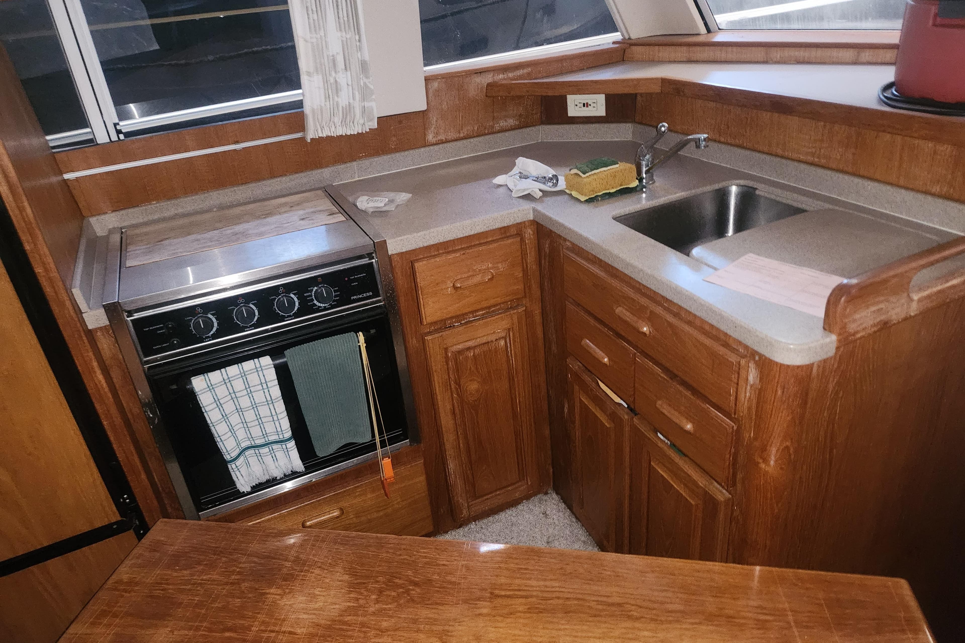 1997 Mainship 350 Trawler kitchen with stove, sink, and wooden cabinetry.