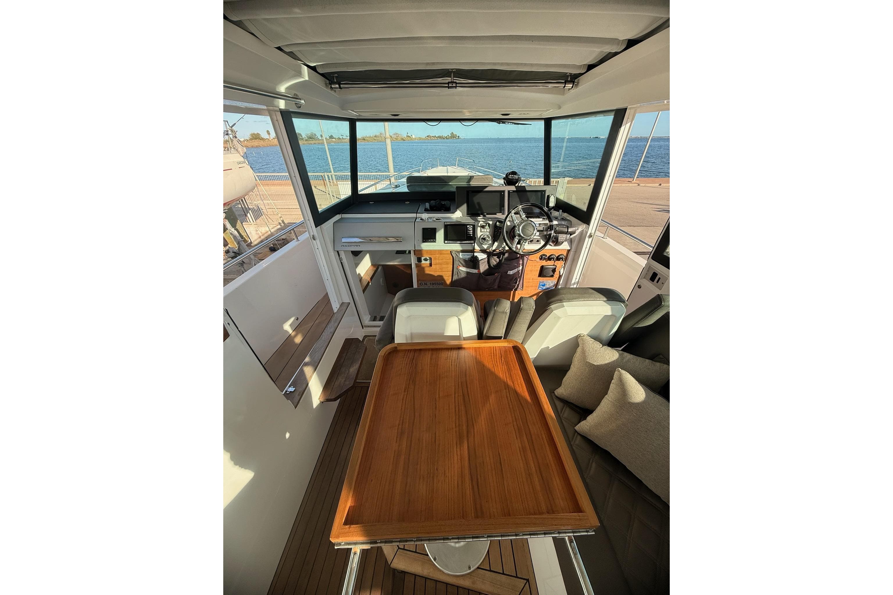 Interior of 2016 Axopar 37 XC CROSS CABIN with wooden table and steering console.