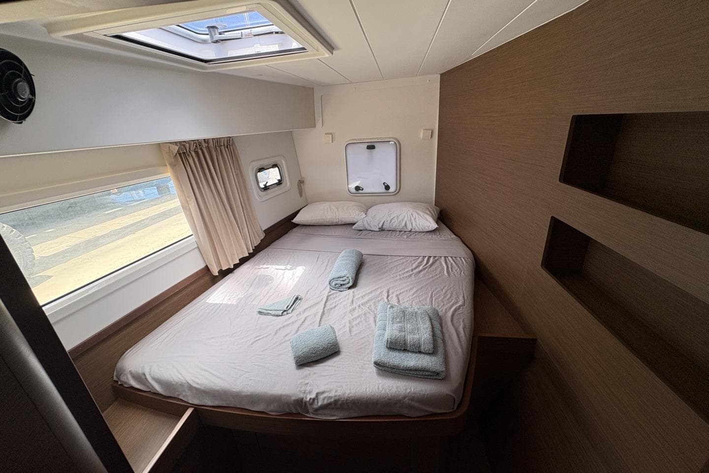 Cozy cabin interior of 2019 Lagoon 42 catamaran with bed and porthole window.