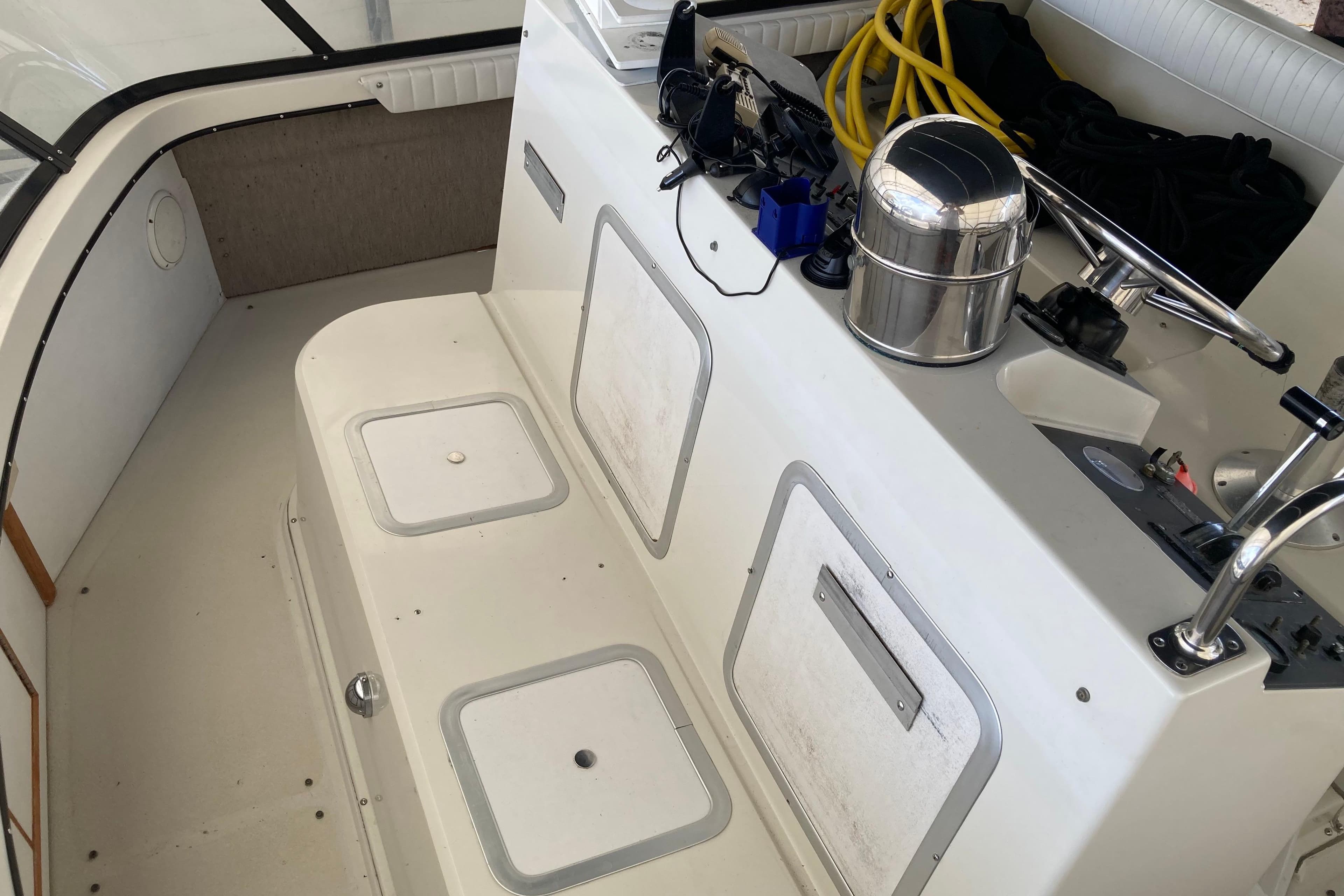 Interior of a 1989 Knight & Carver 3807 boat, featuring storage compartments and equipment.
