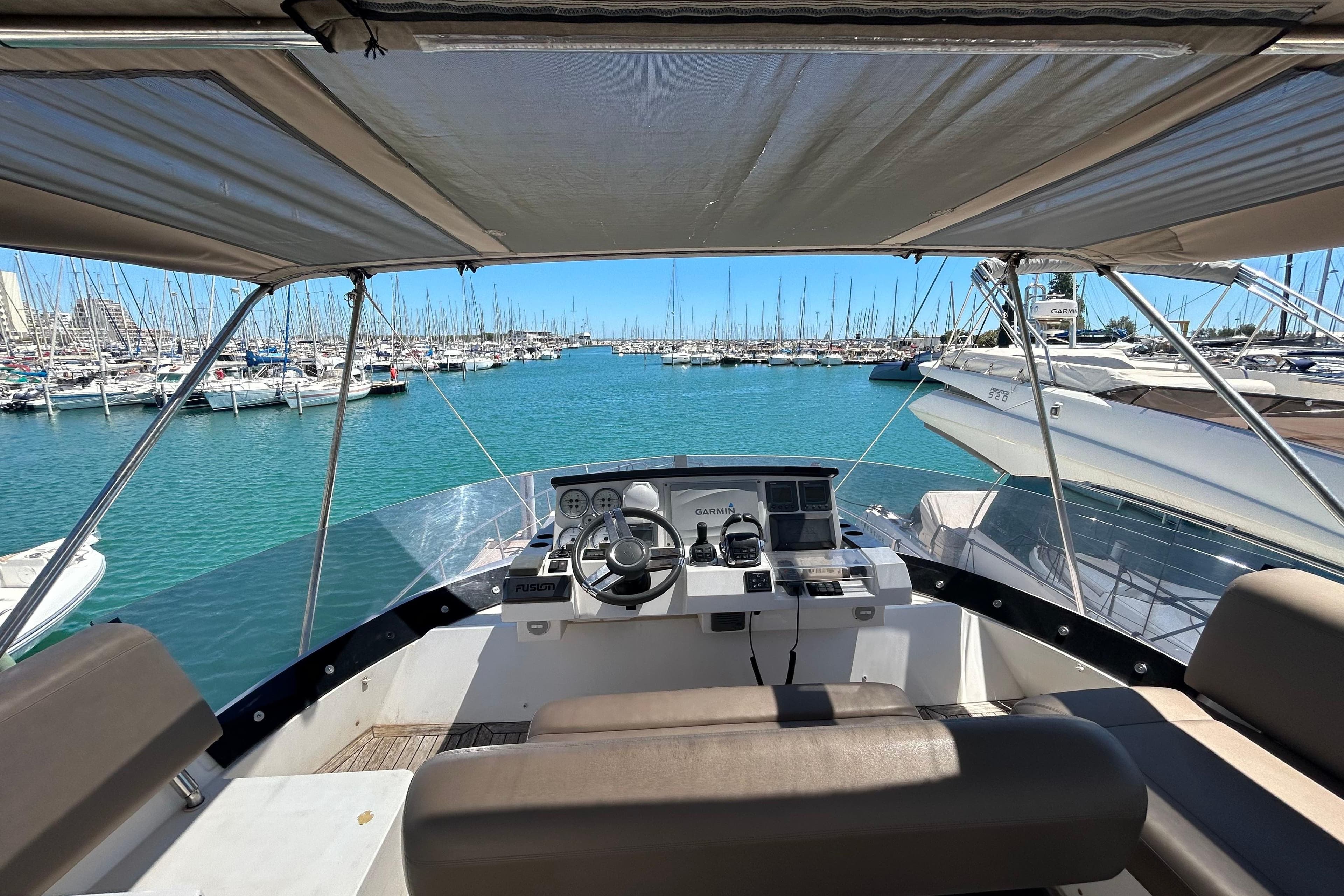 Cockpit view of 2012 Sealine F42 yacht in a marina with clear blue water.