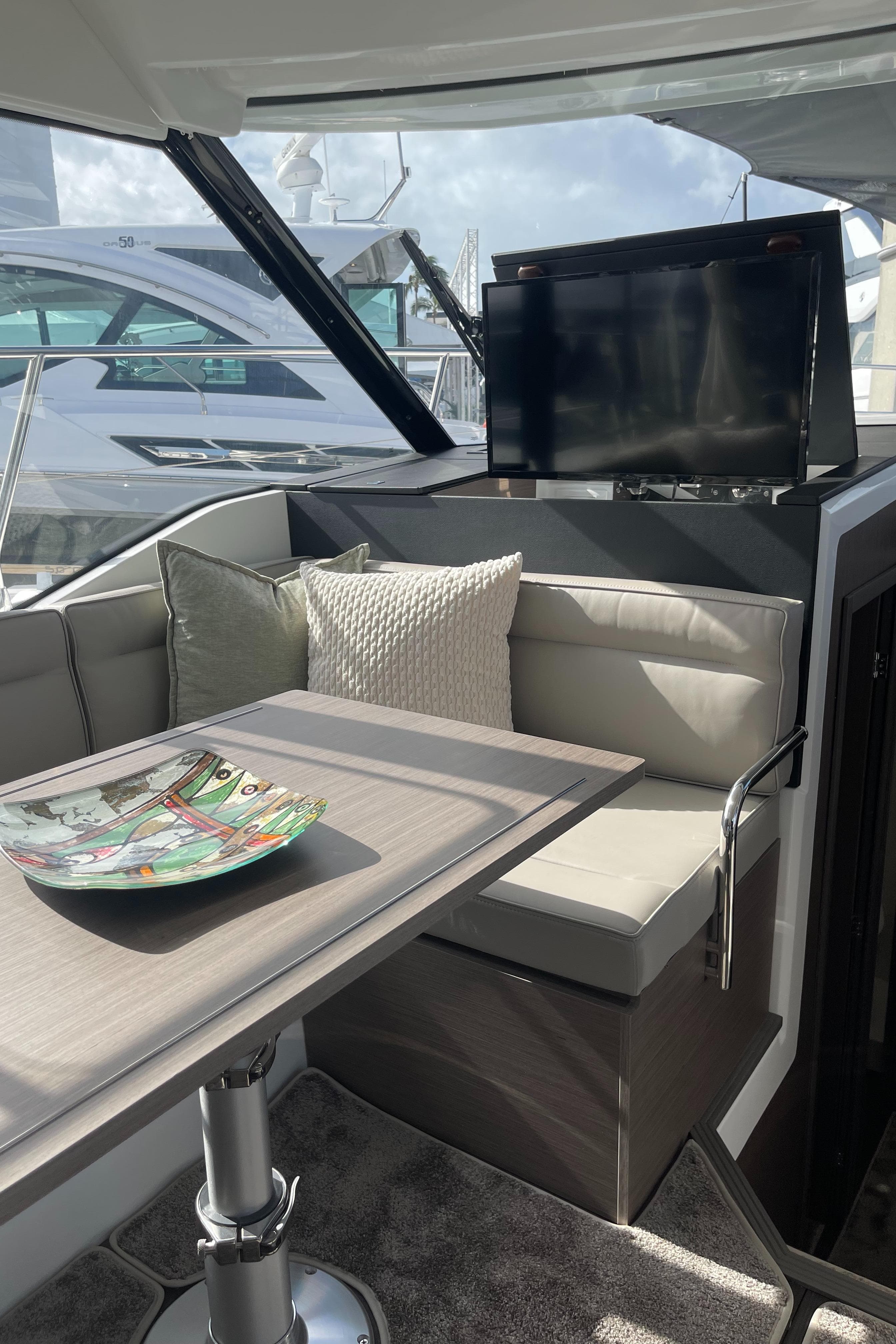 2025 Jeanneau NC 1295 Coupe interior with seating, table, and TV.