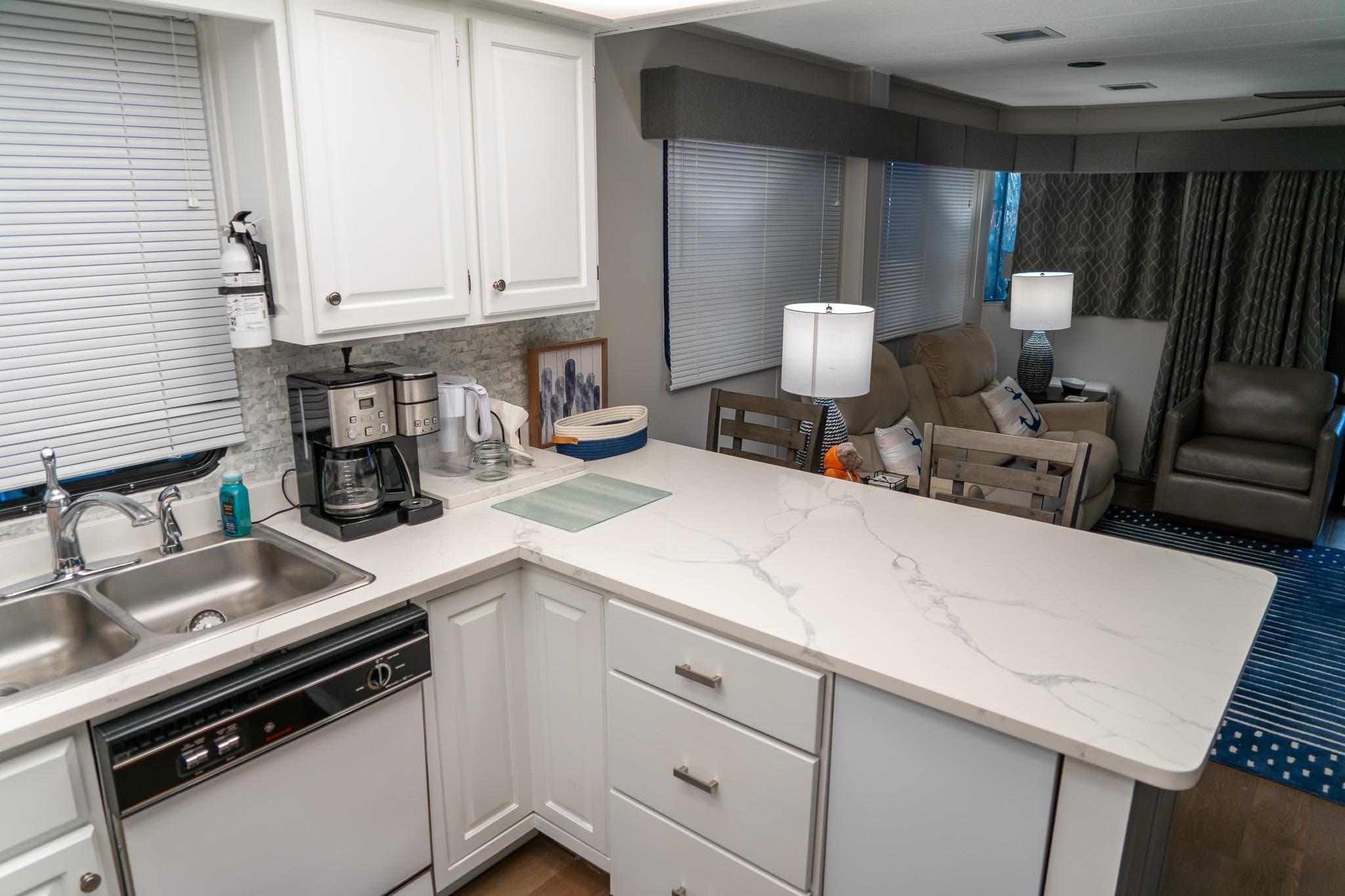 Modern kitchen and living area in 1996 Lakeview houseboat, featuring white cabinetry and cozy seating.