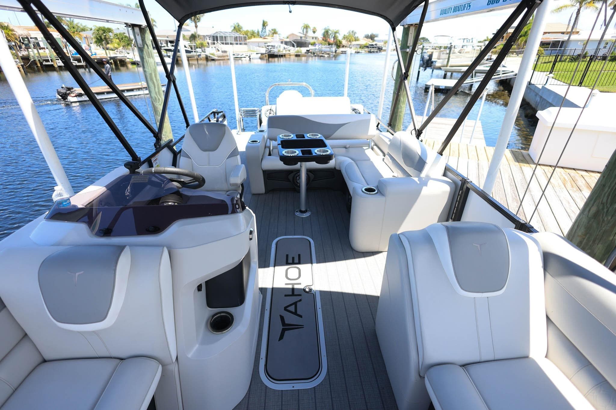2025 Tahoe Pontoon LTZ 23 interior with luxurious seating and modern helm, docked by a scenic waterfront.