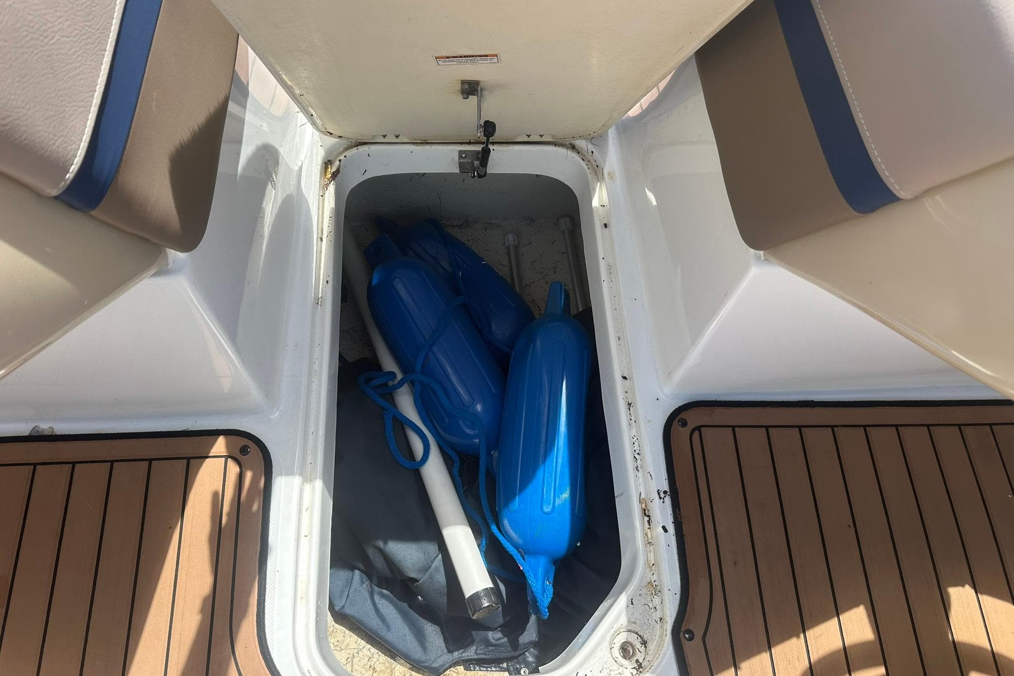 Storage compartment of 2019 Hurricane Sundeck Sport 218 OB with blue boat fenders.