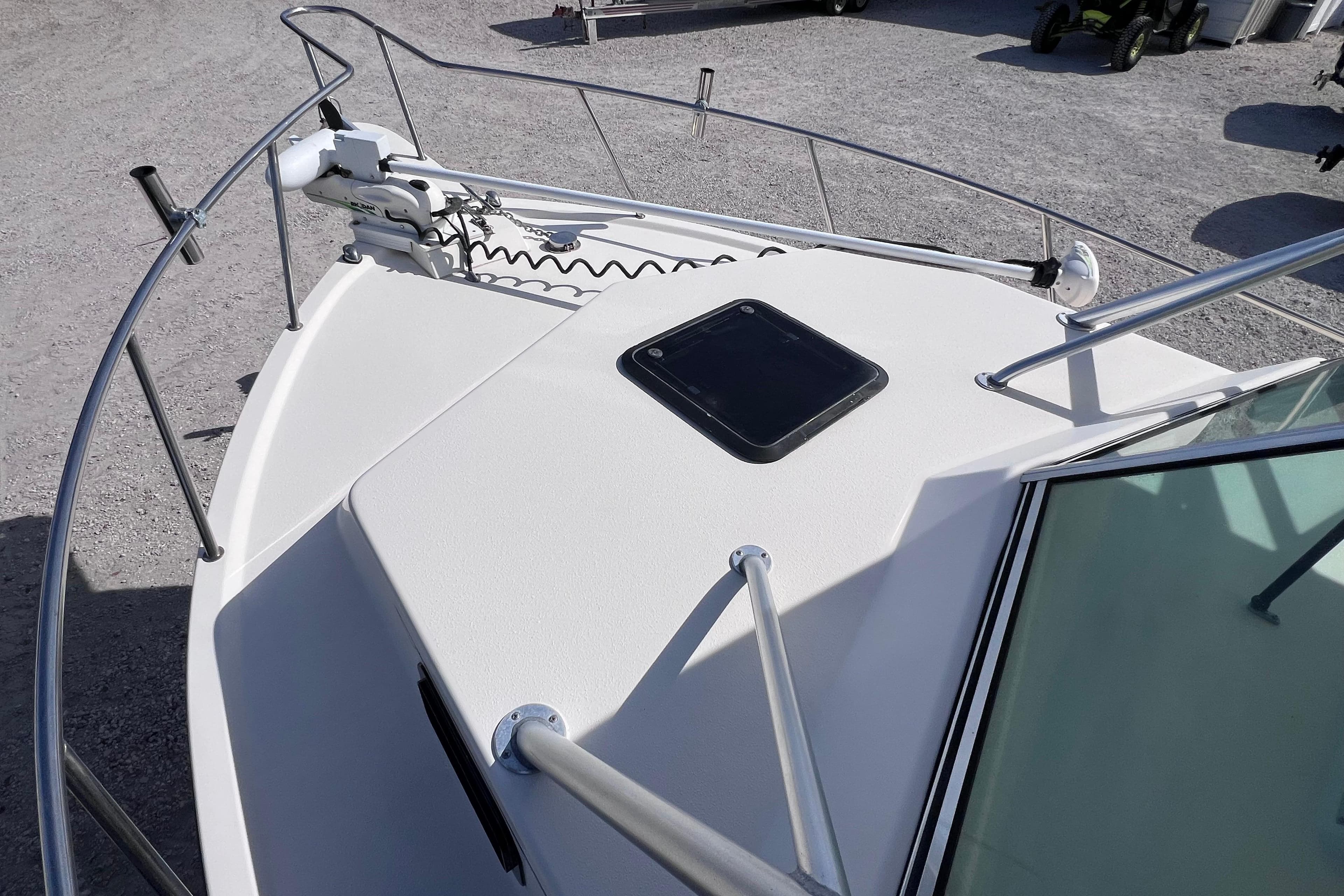 2005 Parker 2510 Walkaround boat deck with railing and hatch, parked on gravel.