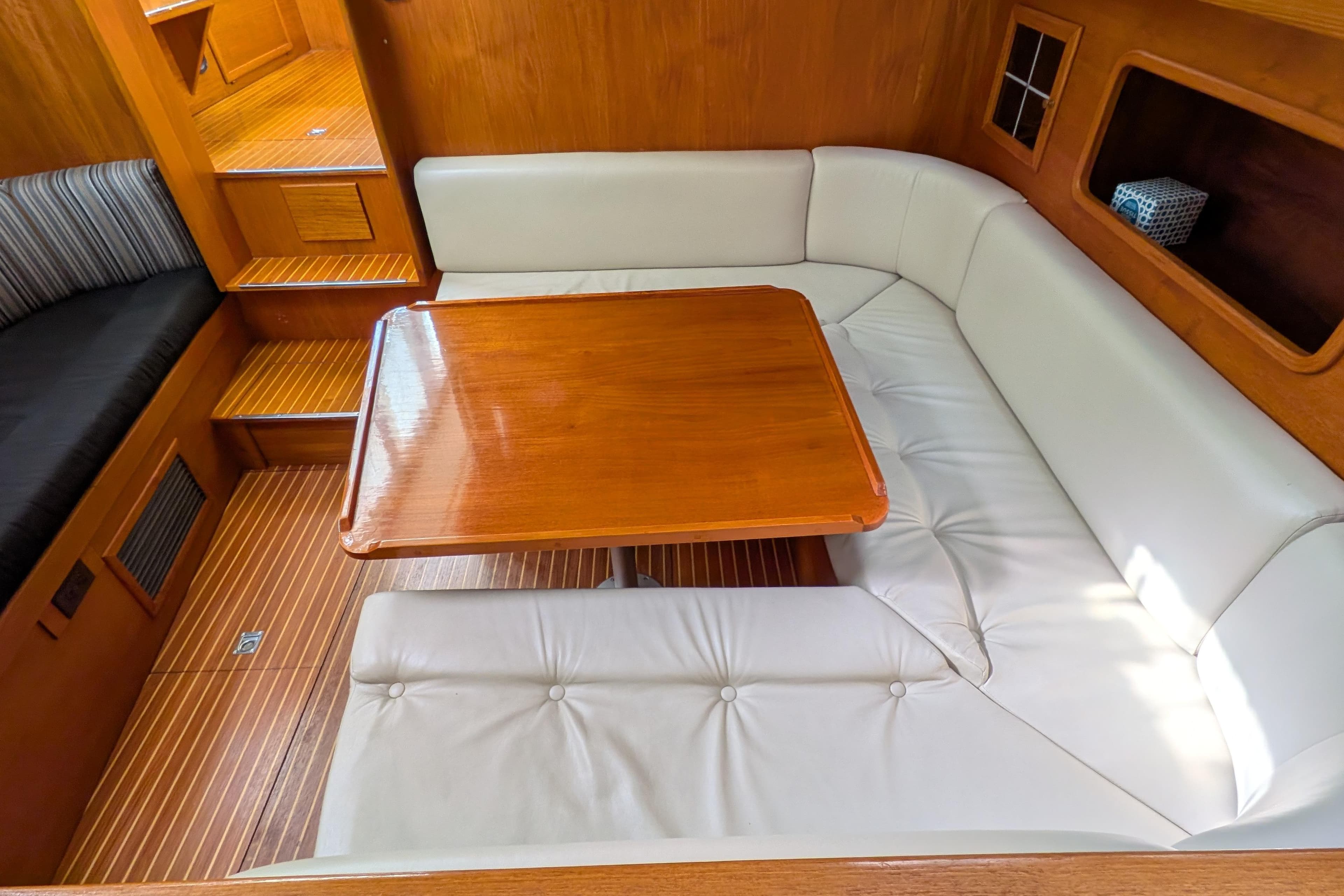 Interior of 1985 Siltala Nauticat 44 yacht with wooden table and white seating.