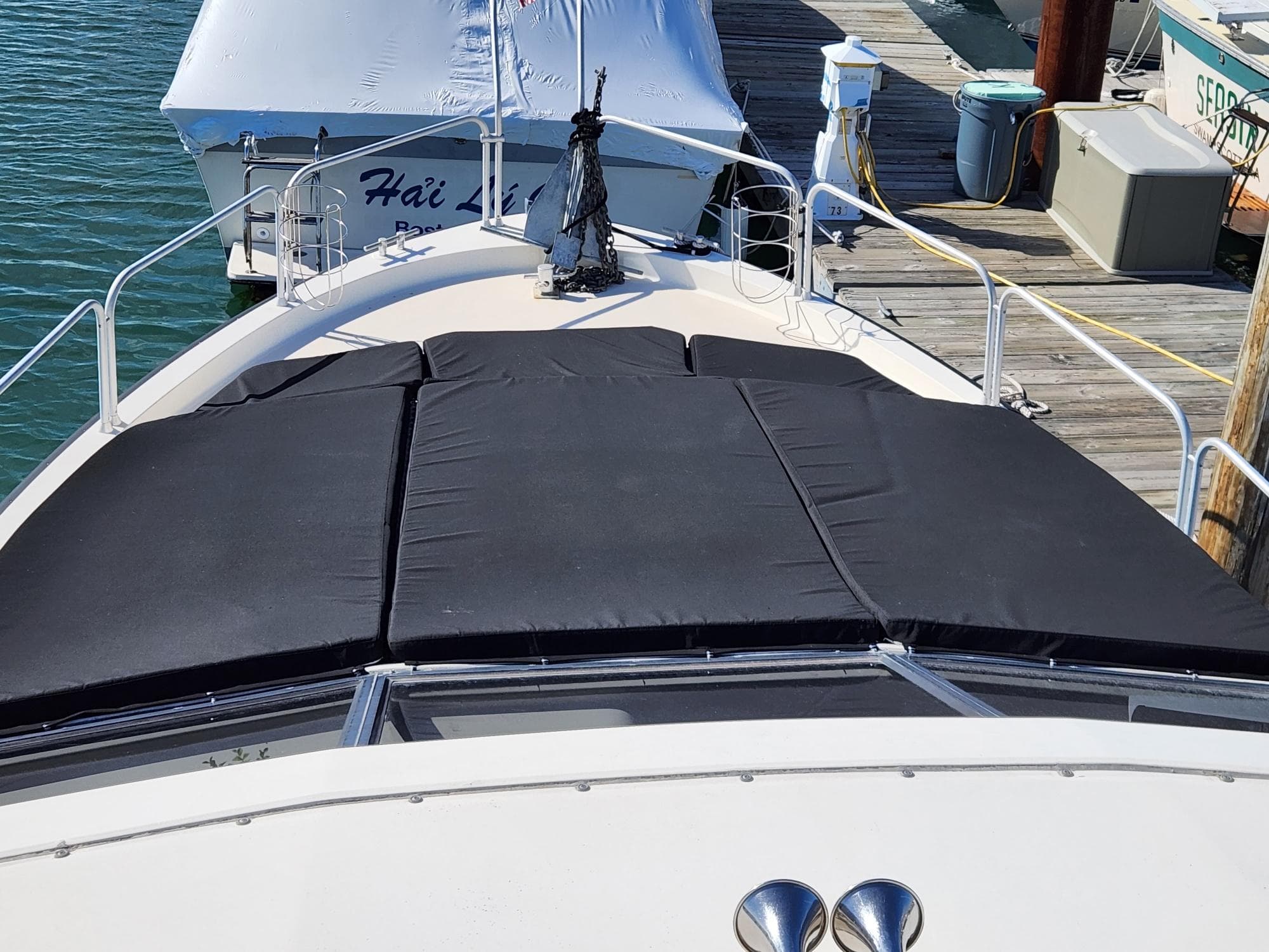 1990 Mainship Mediterranean boat docked, featuring a black sunpad on the bow.