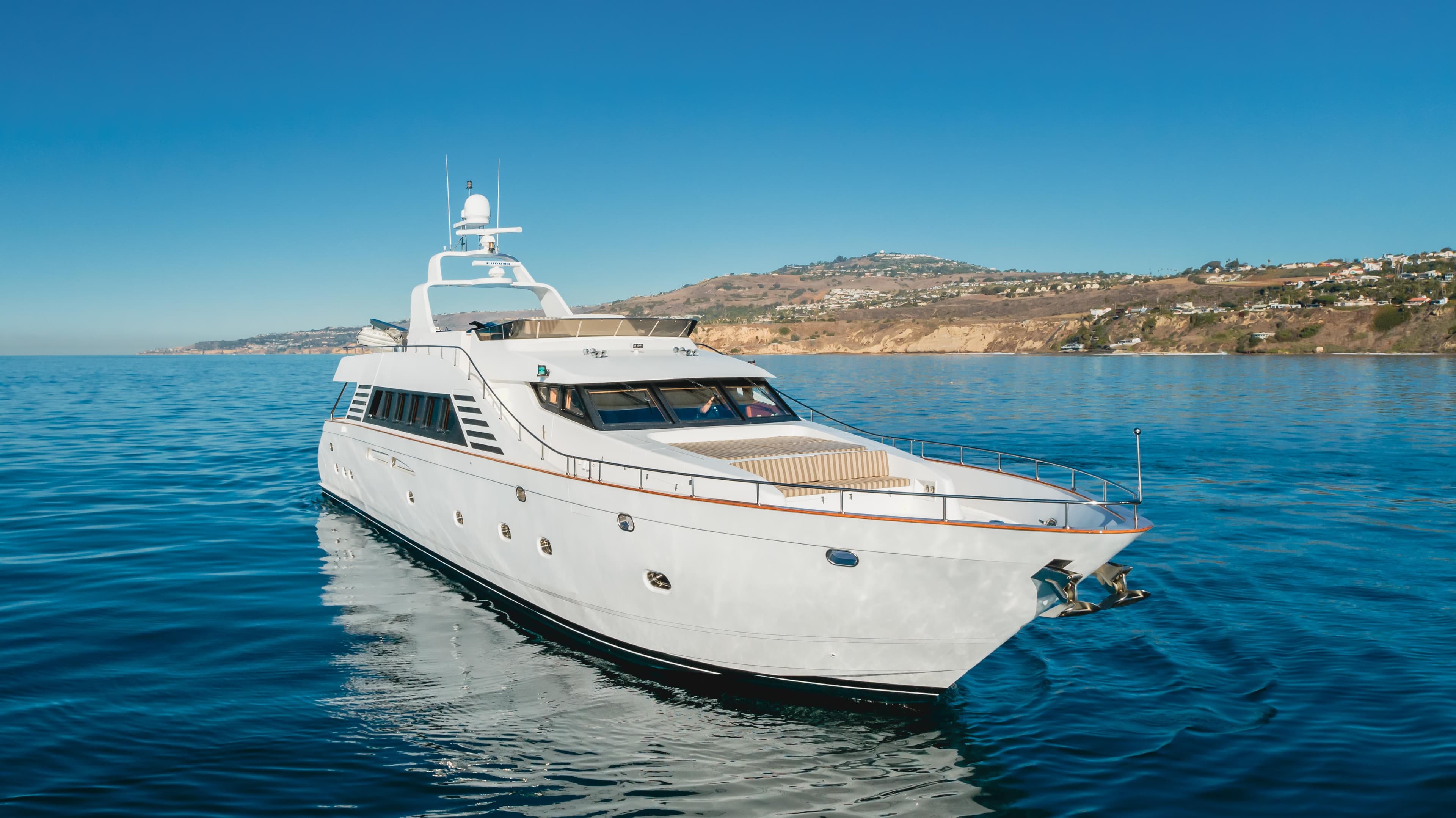 Luxury 2003 TransWorld CUSTOM yacht cruising on clear blue waters near scenic coastline.