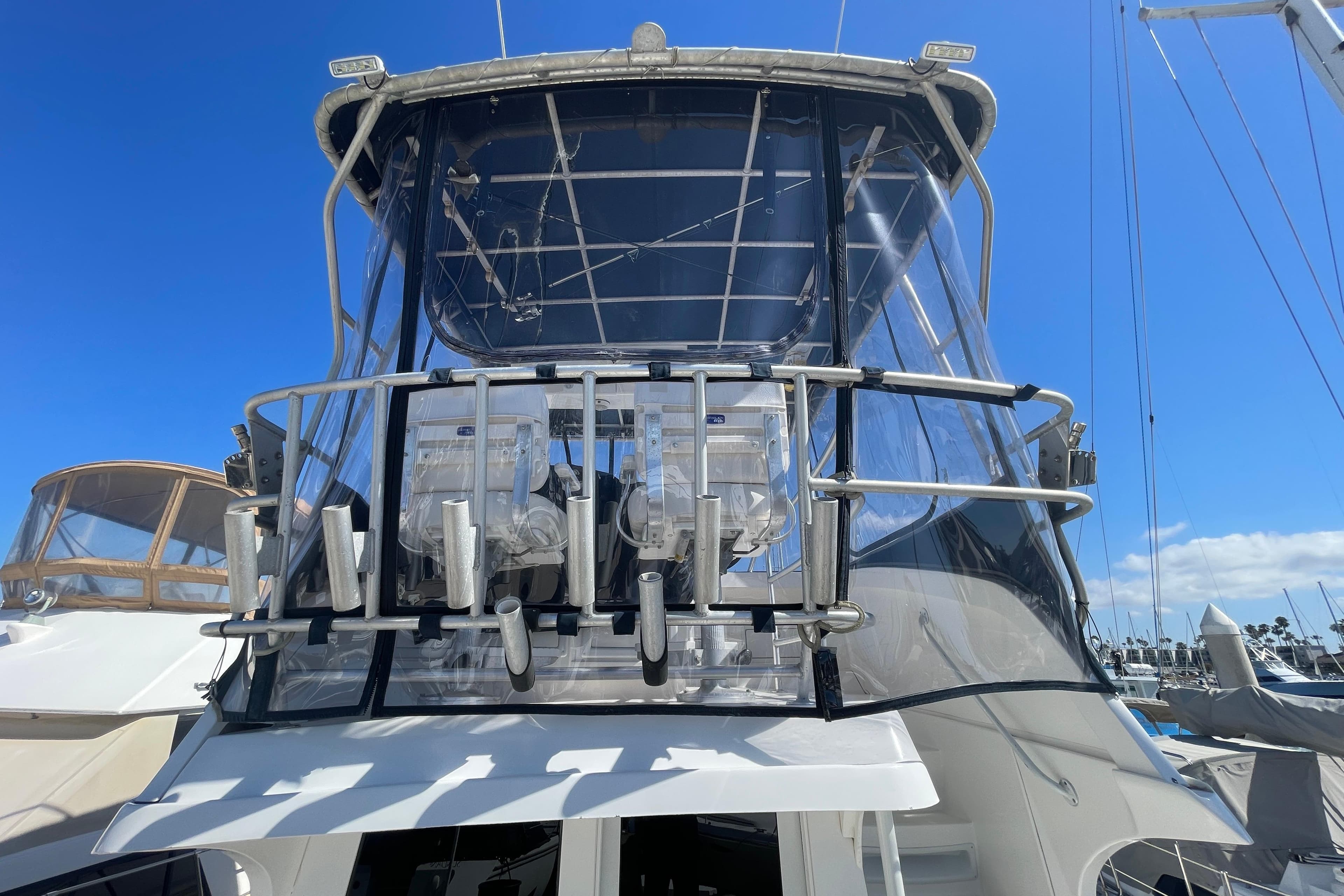 2003 Luhrs 34 Convertible yacht with enclosed flybridge, docked under clear blue sky.