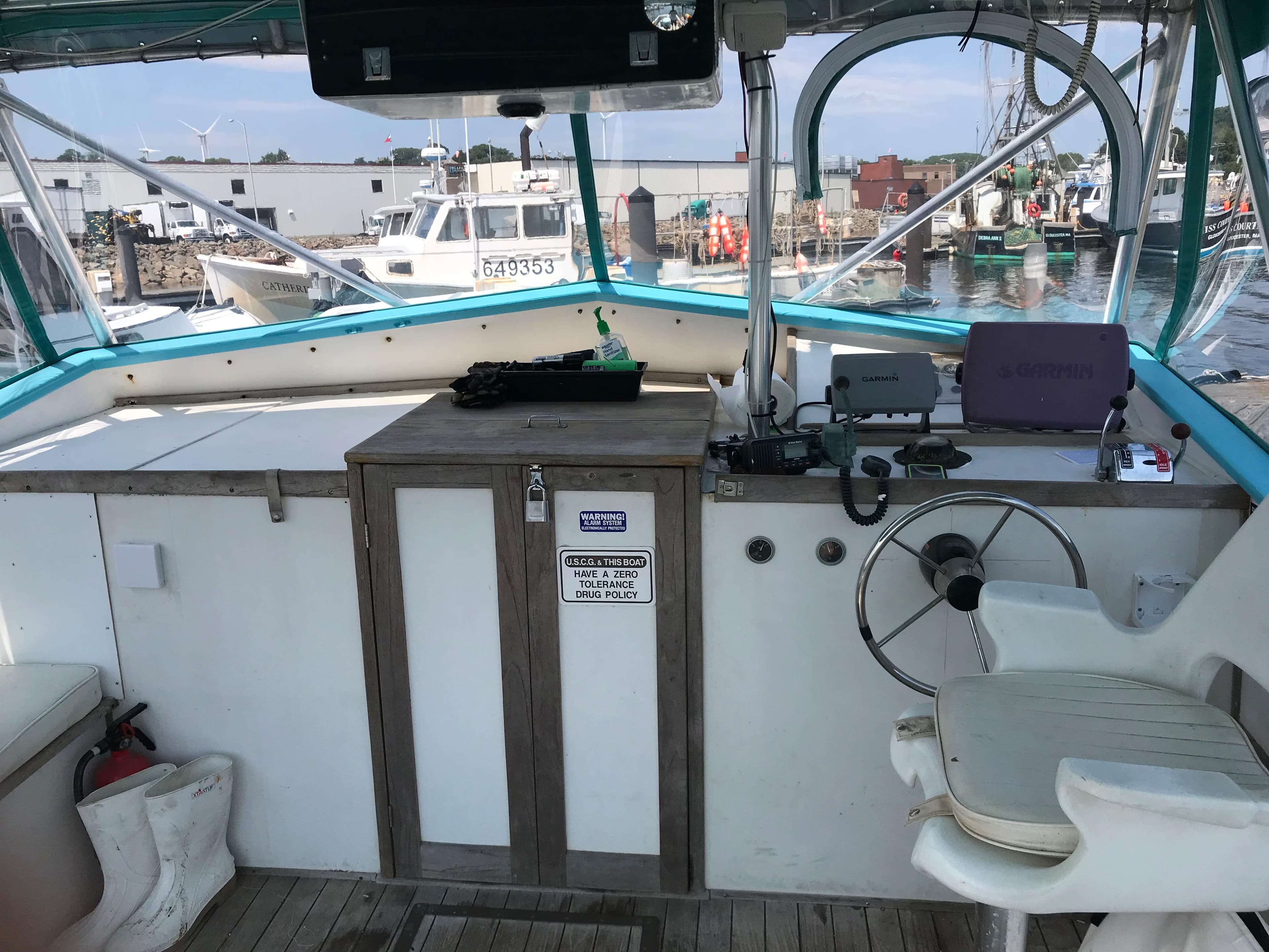1988 JC Provincetown boat helm with steering wheel and control panel at a marina.
