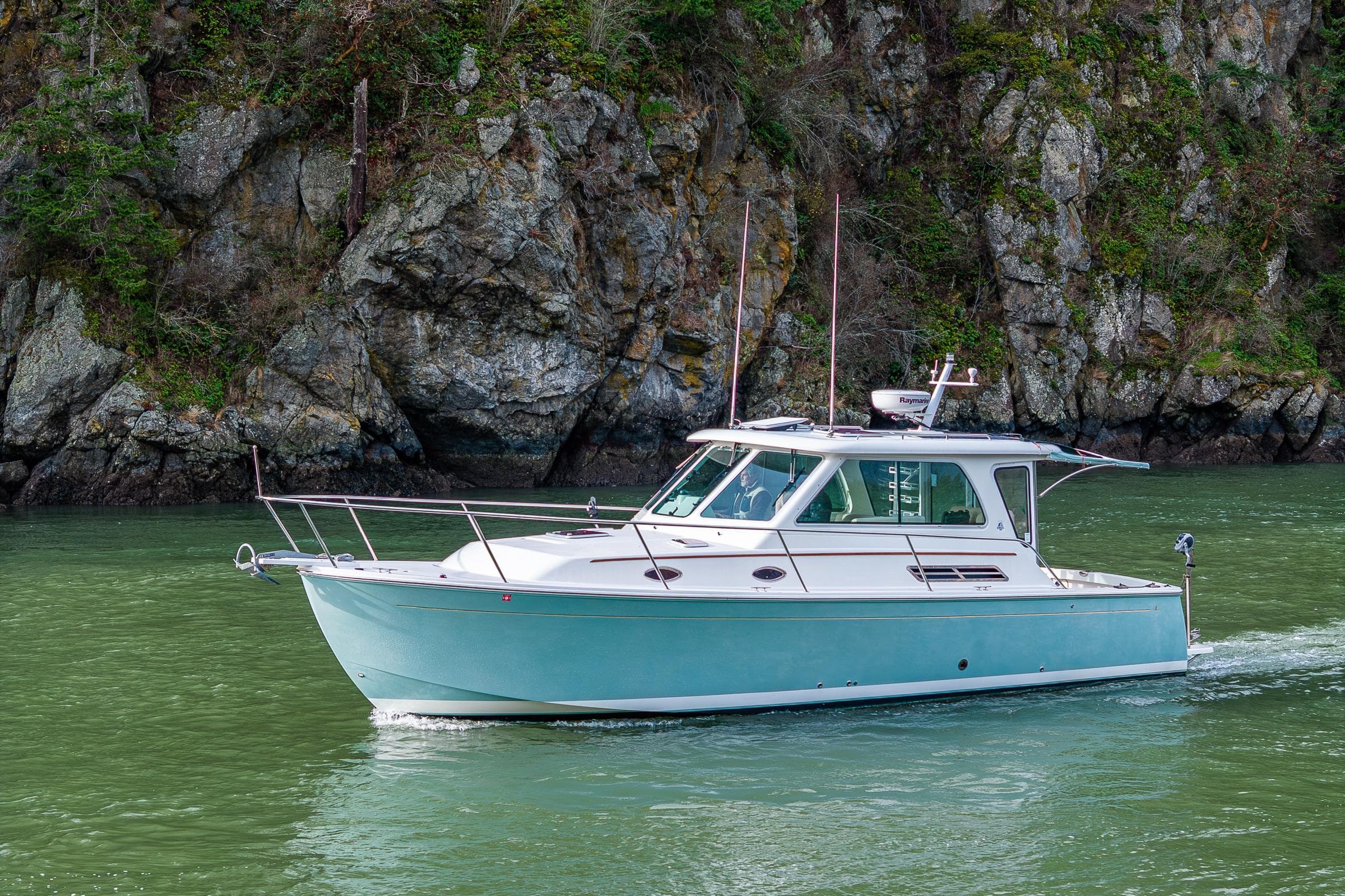 2008 Back Cove 33 boat cruising near rocky shoreline.