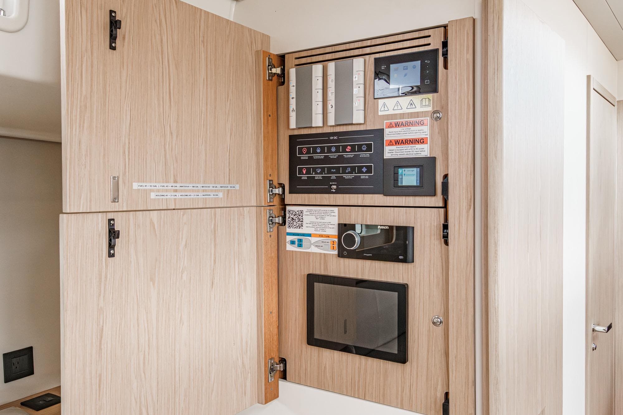 Electrical panel inside 2022 Beneteau Oceanis Yacht 54, featuring control switches and warning labels.