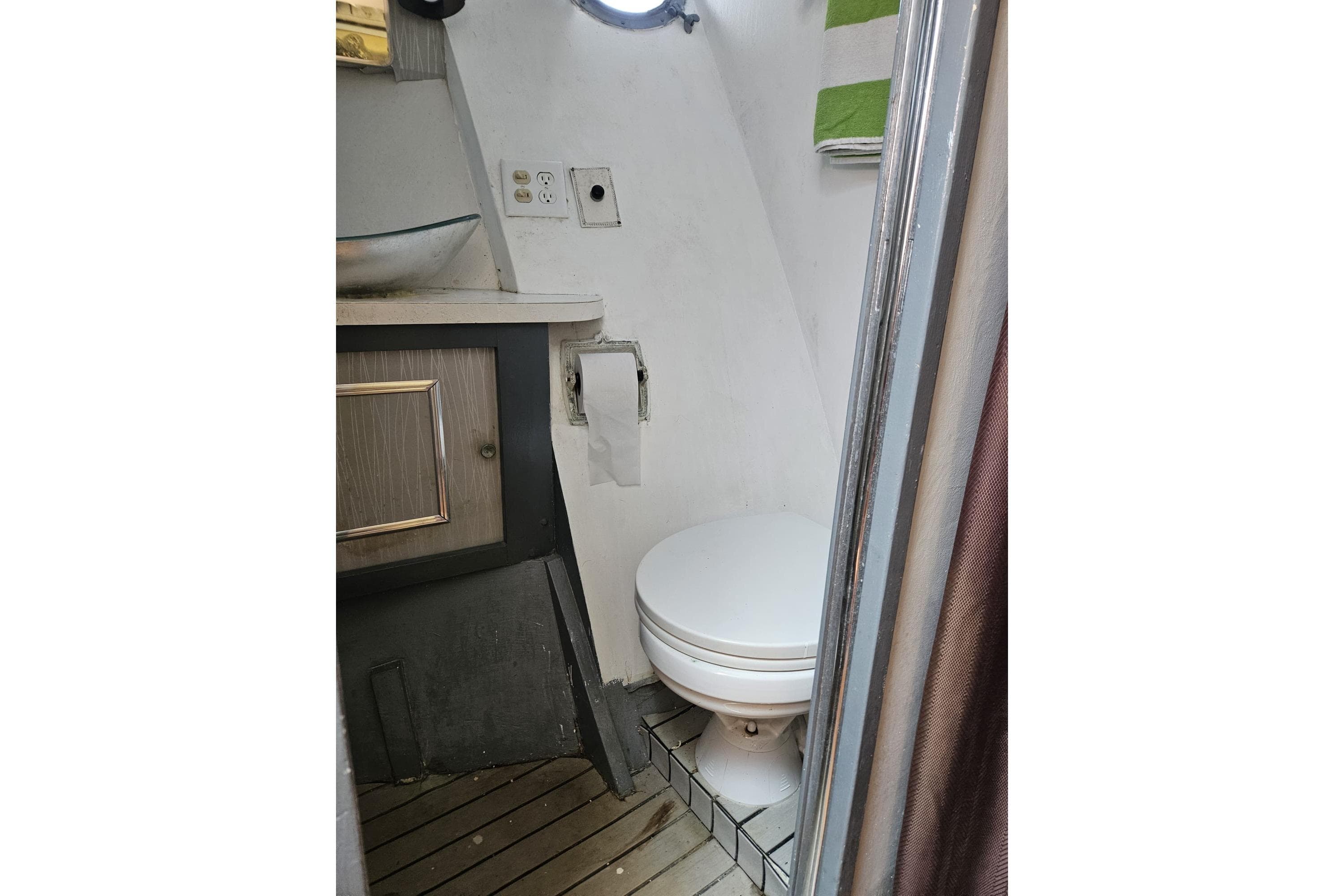 1977 Chris-Craft 52 Constellation bathroom with toilet, sink, and wooden flooring.