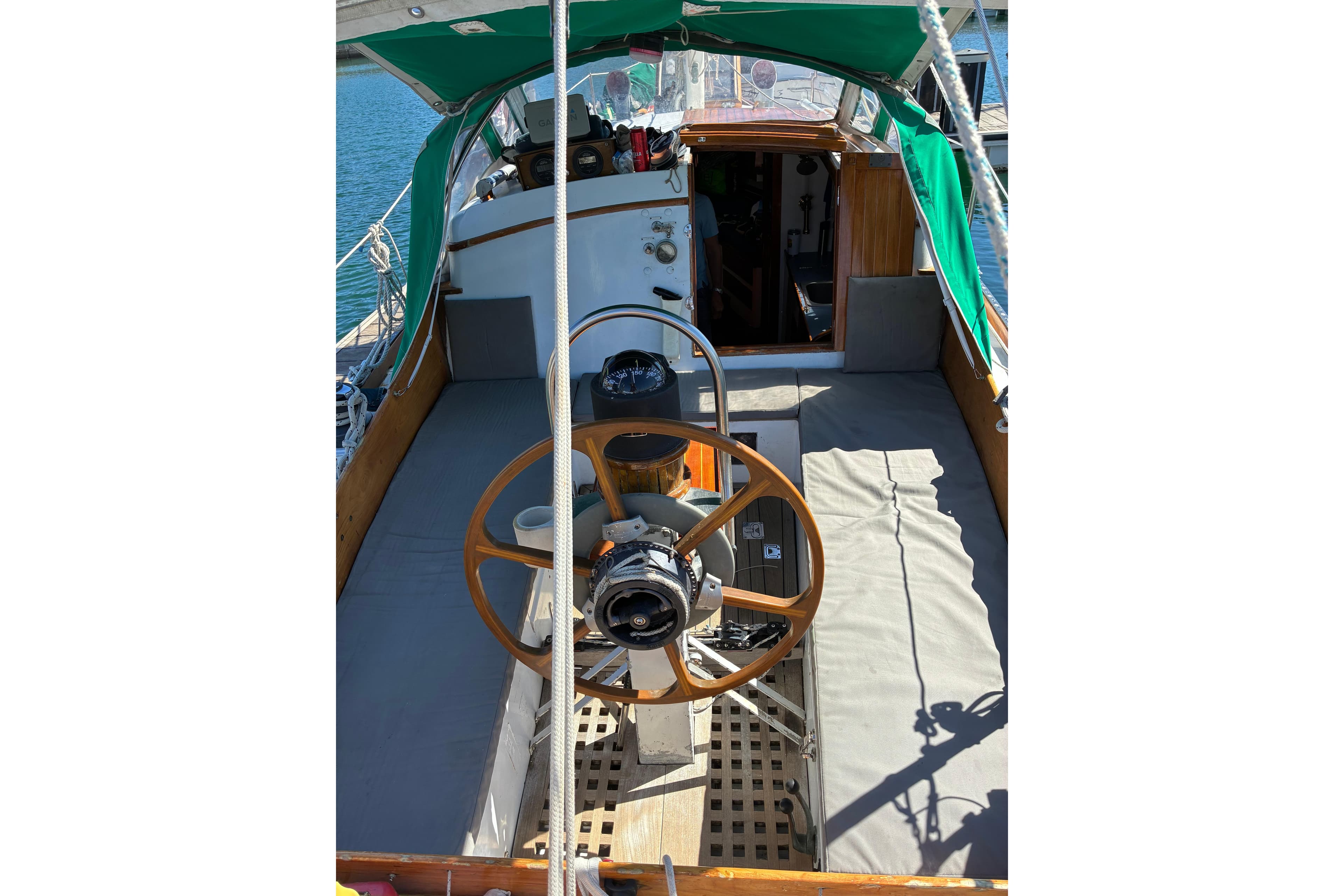 1974 Cheoy Lee Luders Offshore 28 sailboat cockpit with wooden steering wheel and green canopy.