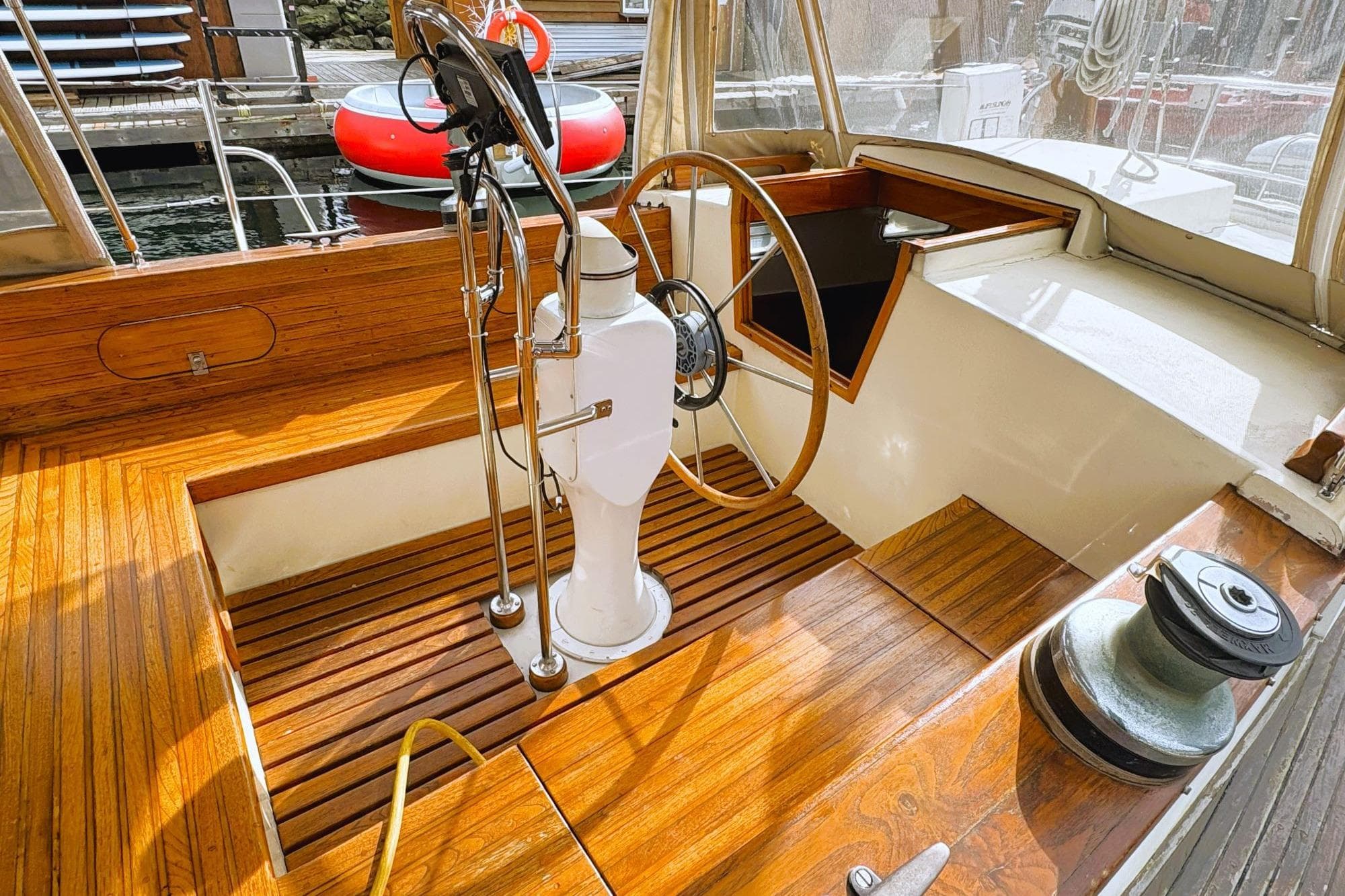 Vintage 1980 Discovery 42 yacht cockpit with wooden deck and steering wheel.