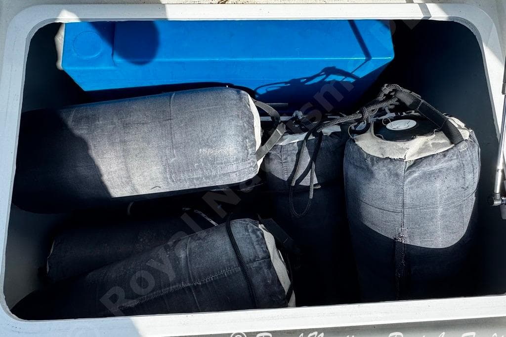 Storage compartment of a 2018 Lagoon 42 with fenders and a blue container.