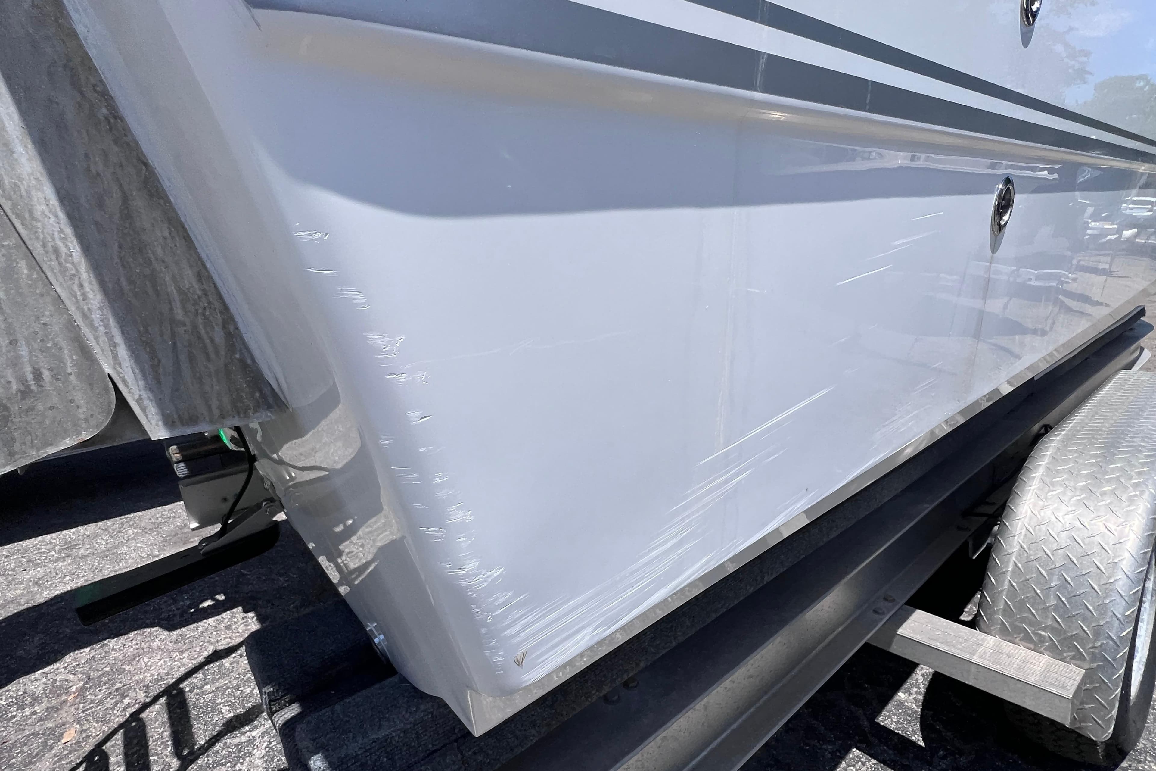 2023 Twin Vee 240 GFX CC boat hull with visible scratches on trailer.