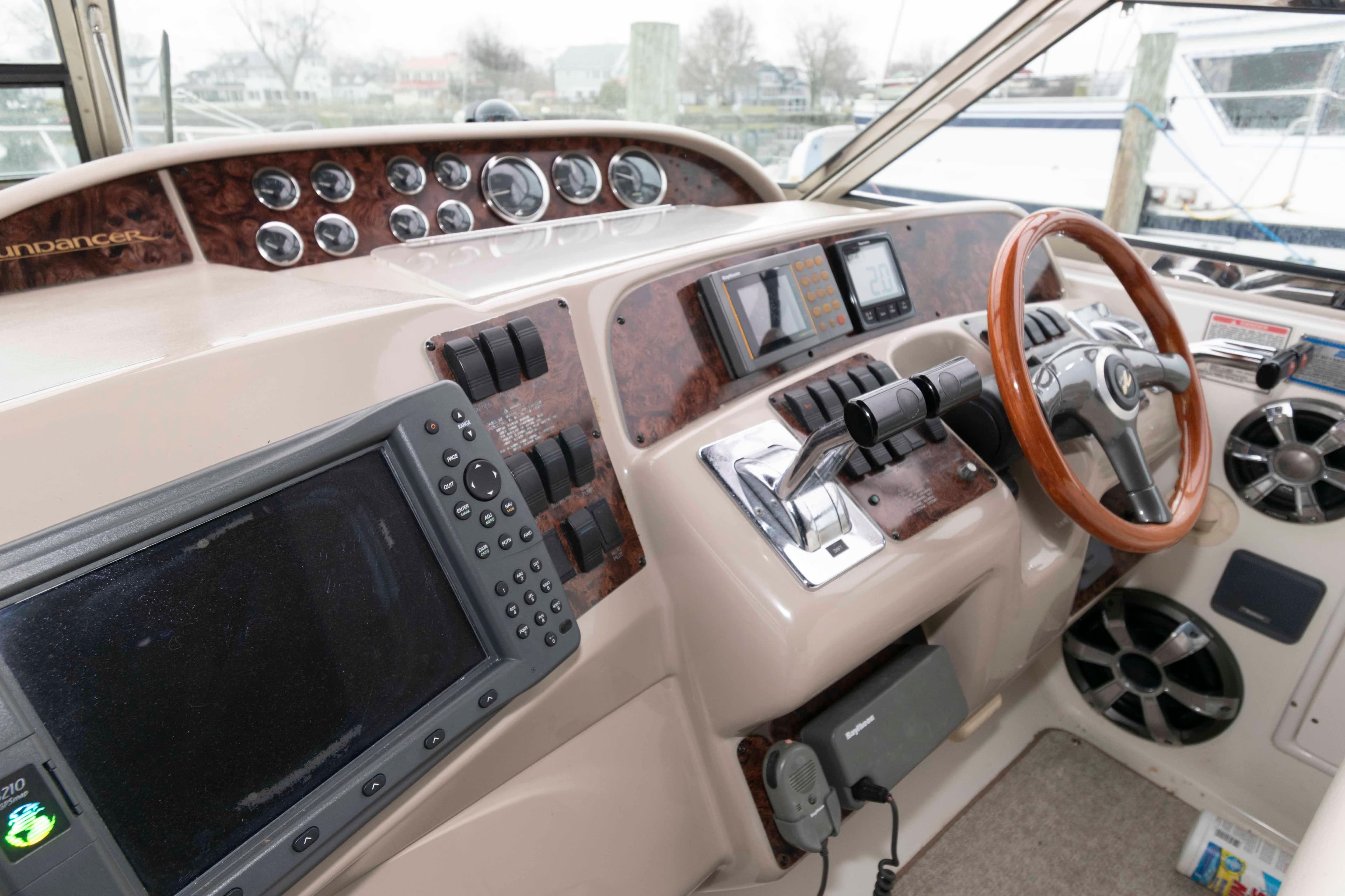 1999 Sea Ray 370 Sundancer helm with wood accents and modern navigation equipment.