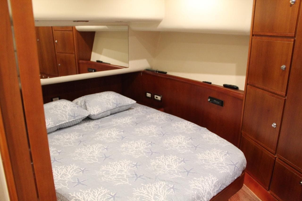 Luxurious cabin interior of 2009 Bertram 510 yacht with cozy bedding and wooden cabinetry.